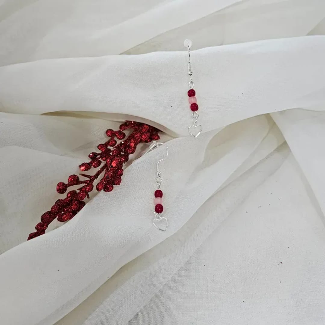 White fabric with red beaded earrings and a red glitter sprig