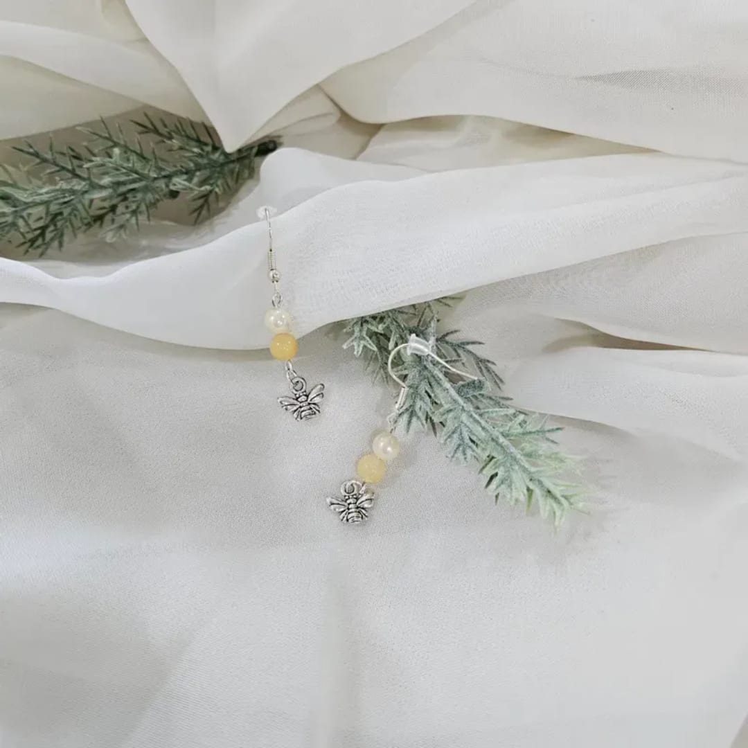 White fabric with faux greenery and dangling bee earrings