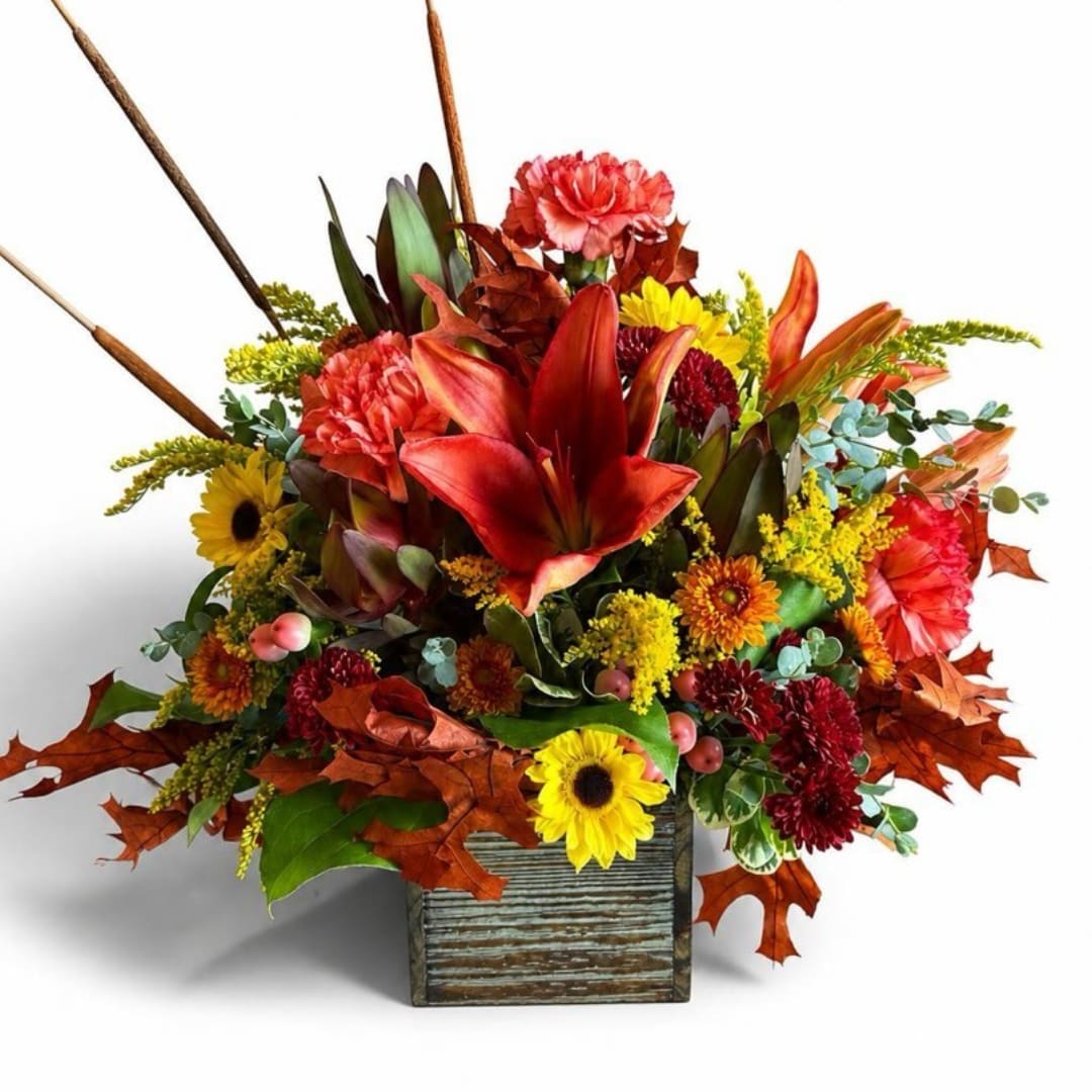 Autumn floral arrangement with red lilies and yellow sunflowers in a rustic wooden container