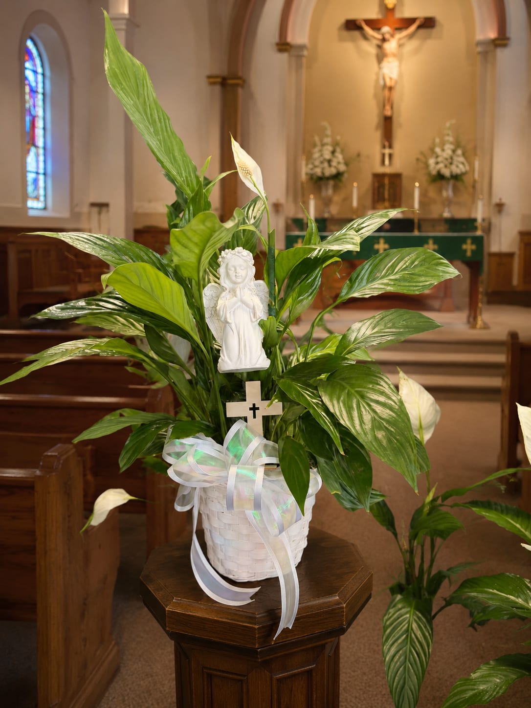 White peace lily plant in a basket with a ribbon and angel figurine