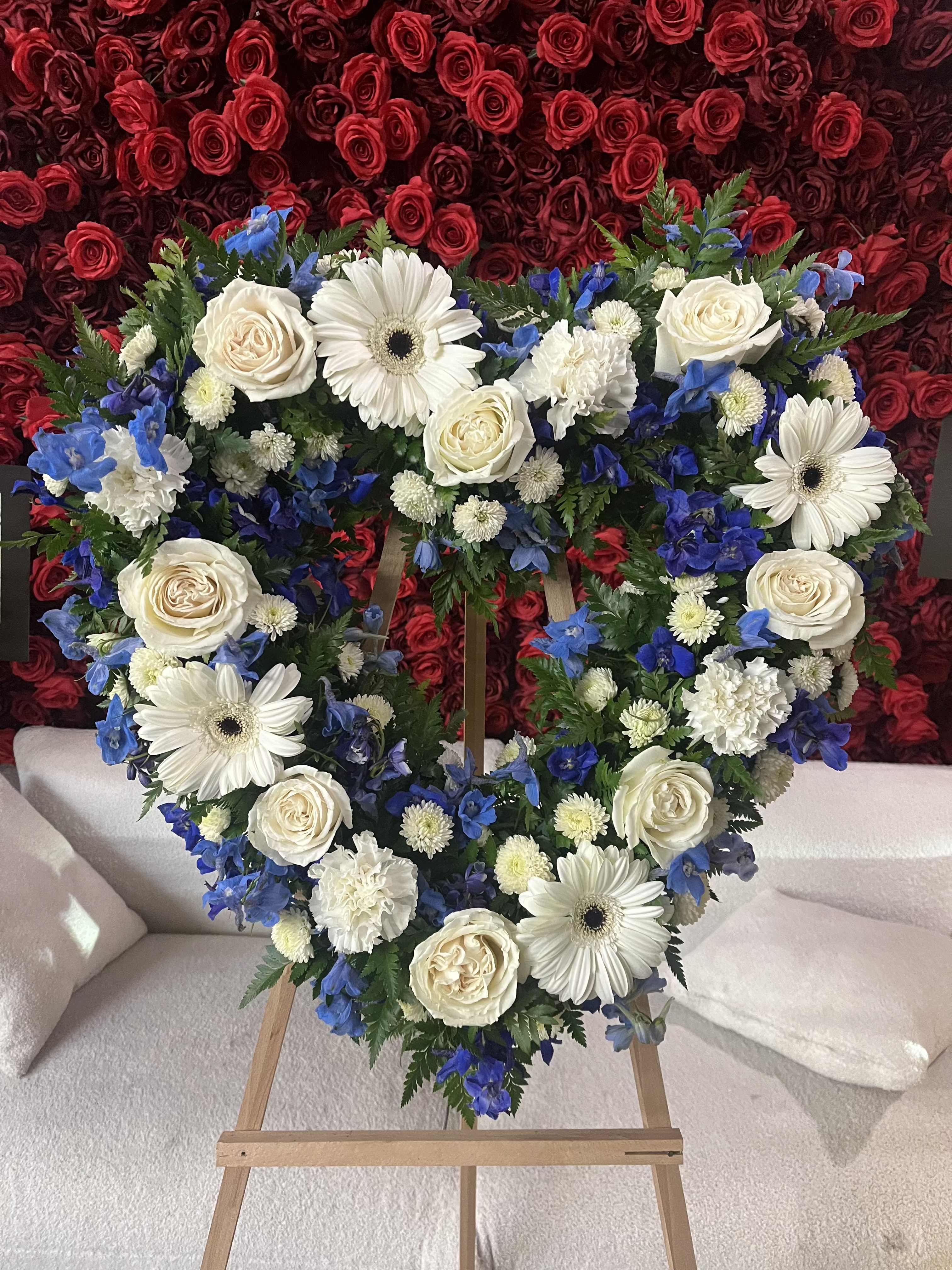 Heart-shaped floral wreath with white roses, daisies, and blue flowers