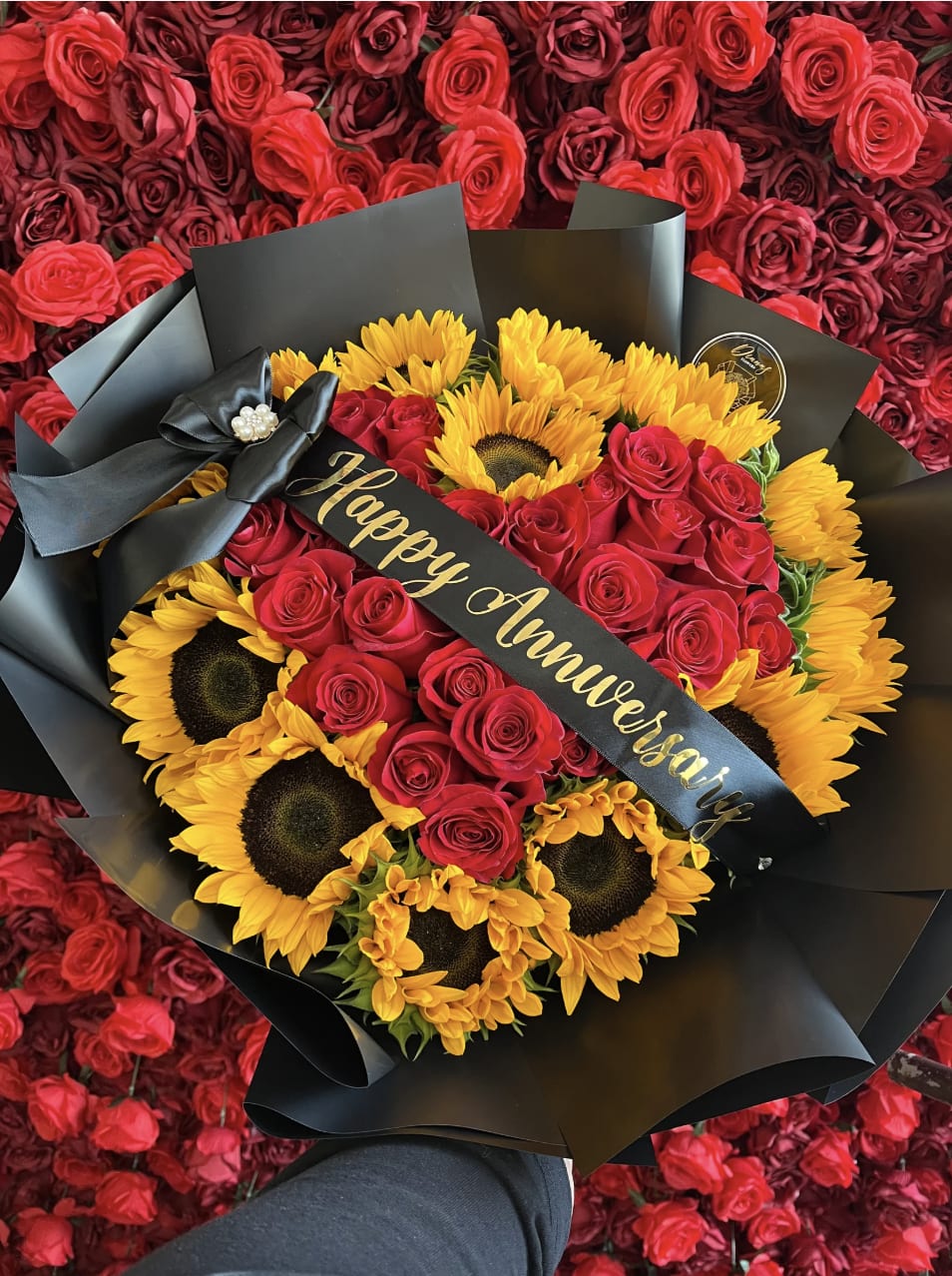 Bouquet of red roses and yellow sunflowers wrapped in black paper