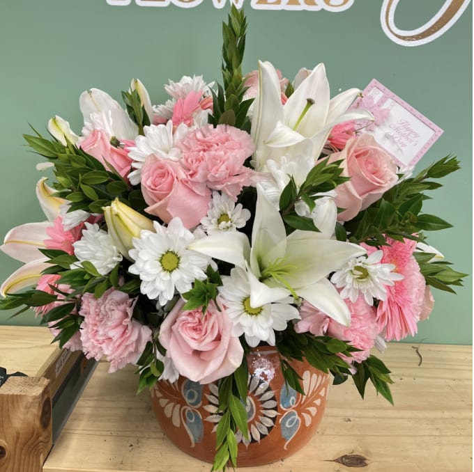 Pink roses and white lilies arranged in a painted ceramic pot