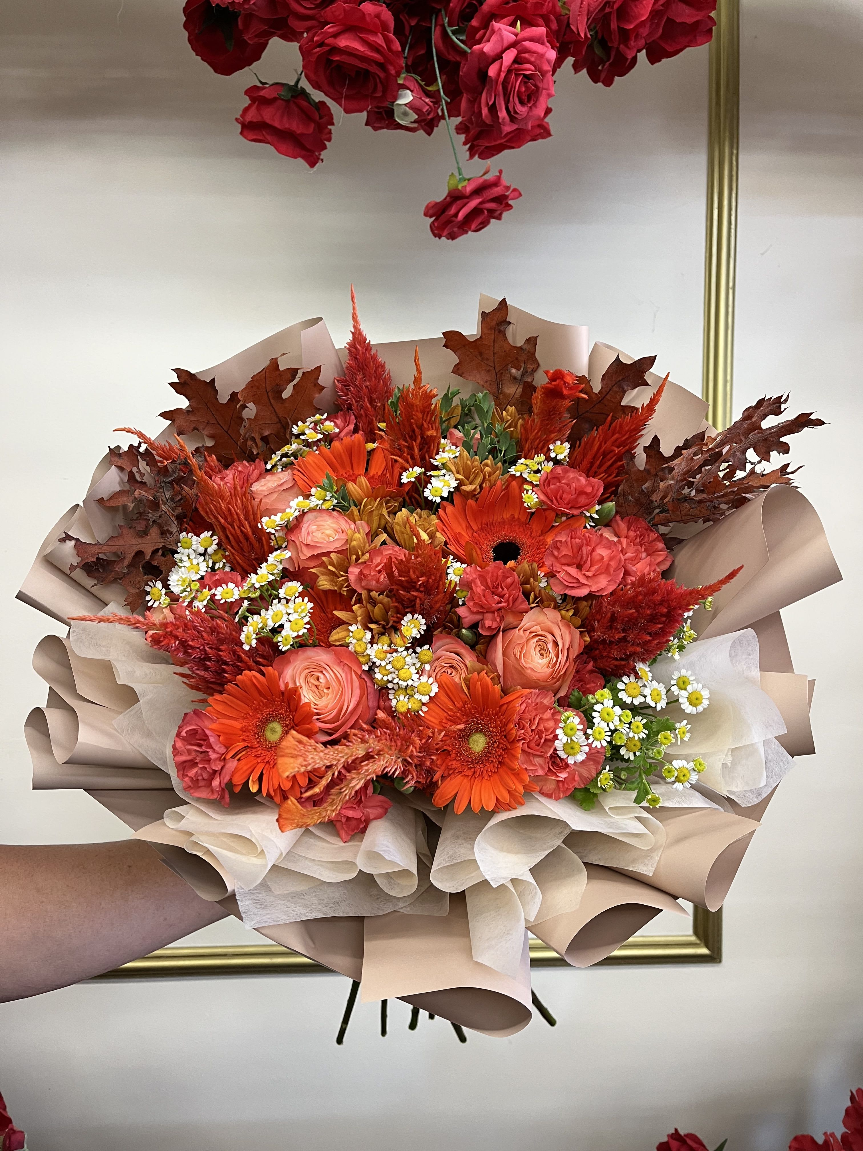 Bouquet of orange and pink flowers wrapped in beige paper