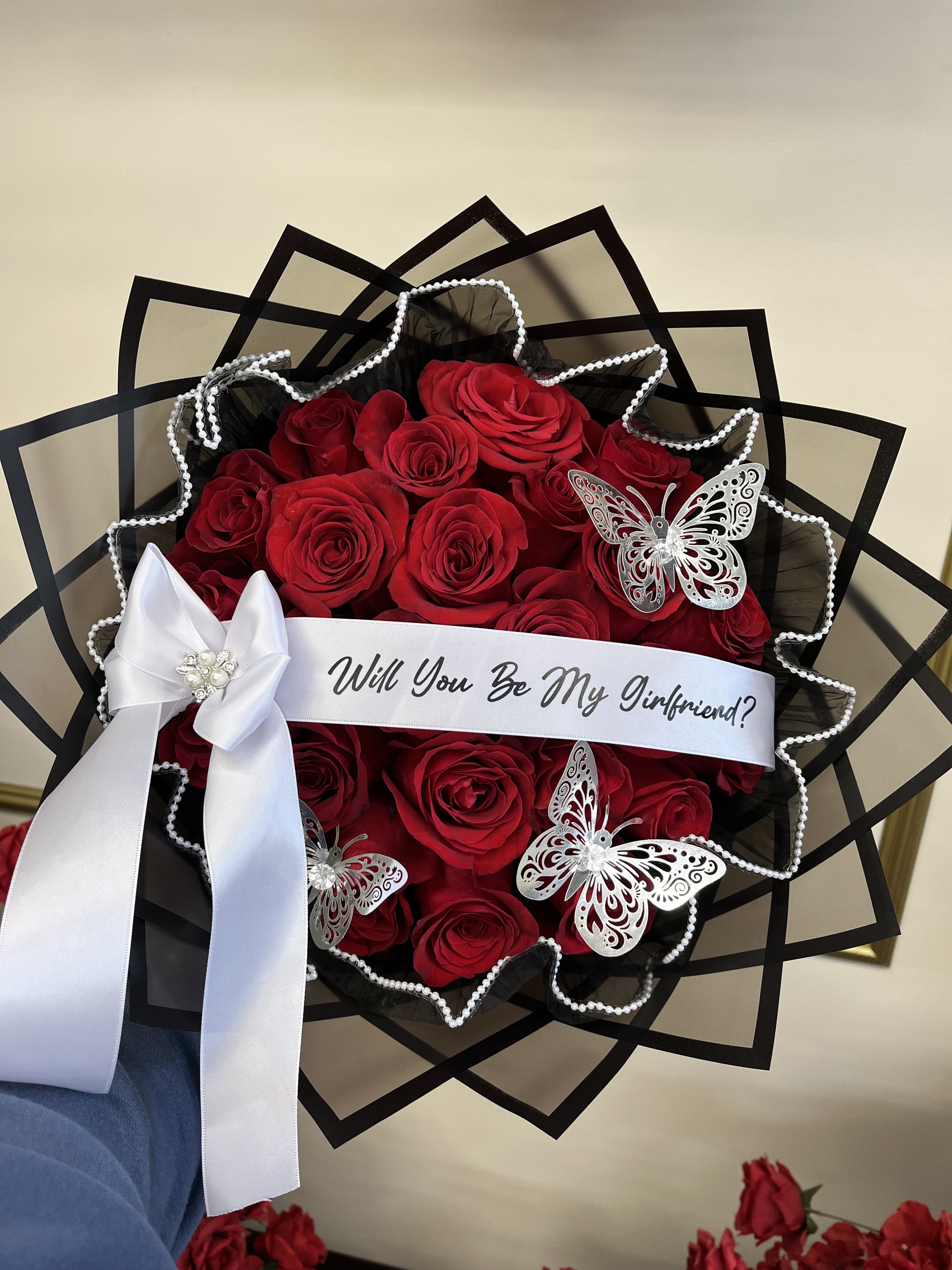 Bouquet of red roses with a white ribbon and butterfly decorations
