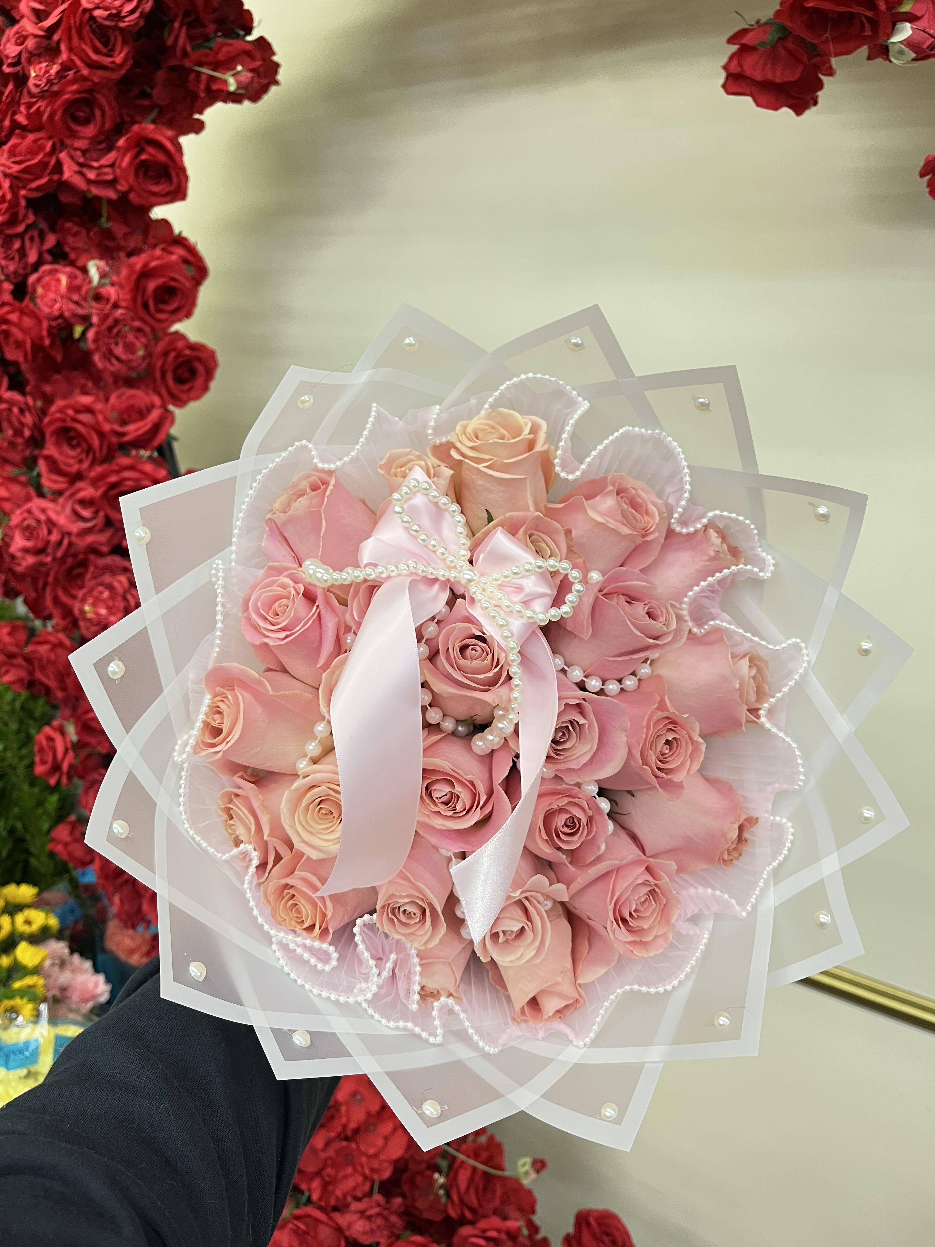 Pink rose bouquet wrapped in sheer paper with a satin ribbon and pearl accents
