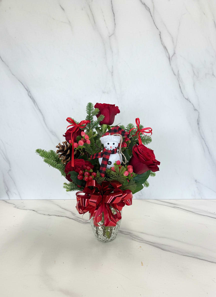 Christmas bouquet of red roses with a snowman ornament in a glass vase
