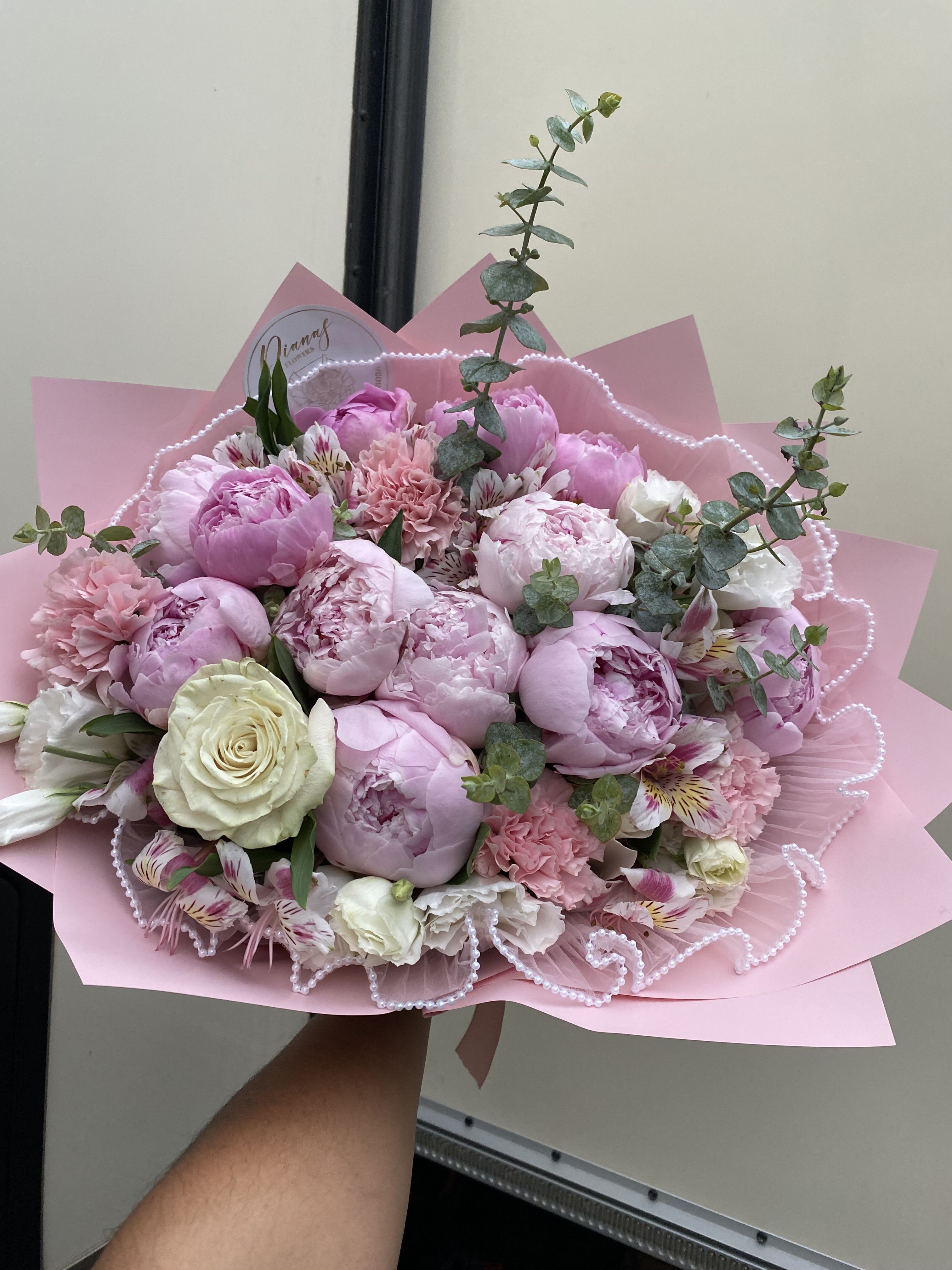 Pink bouquet of peonies and roses wrapped in pink paper