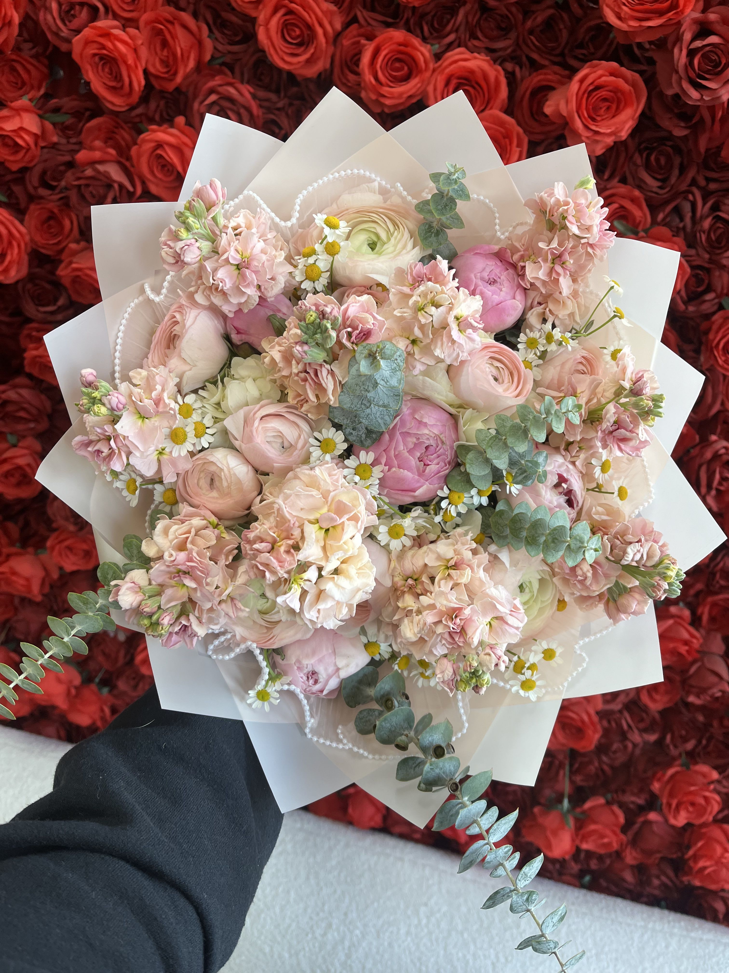 Pink bouquet with roses, ranunculus, and small daisies in white wrap