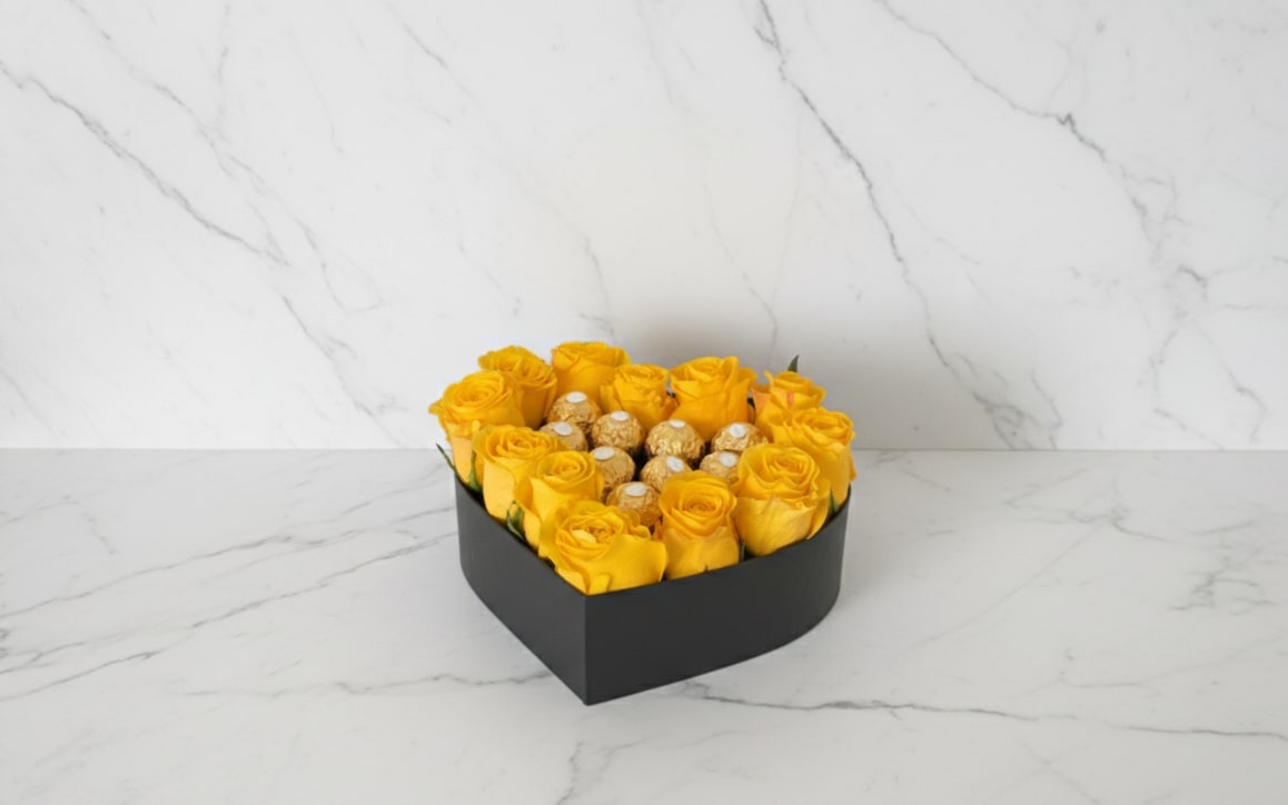 Heart-shaped box of yellow roses with chocolates in the center