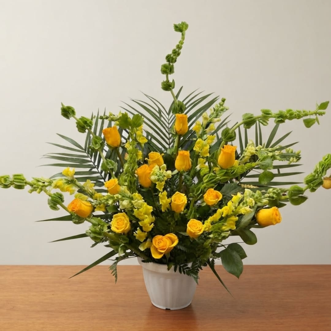 Yellow roses and snapdragons arranged in a white pot