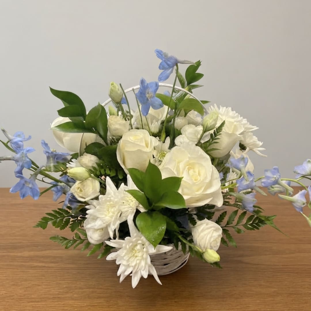 White roses and chrysanthemums in a white basket with blue flowers