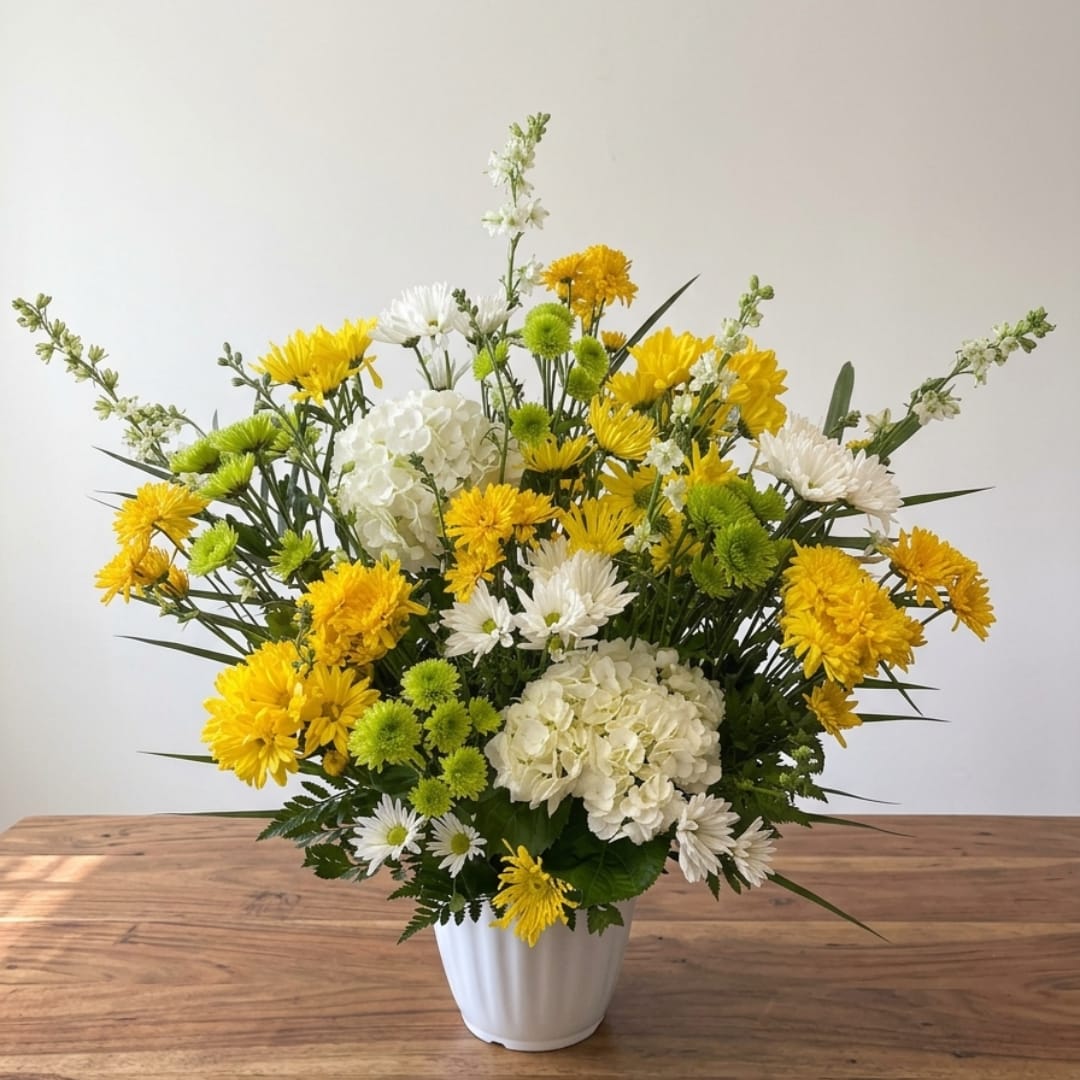 Yellow and white mixed flower arrangement in a white vase