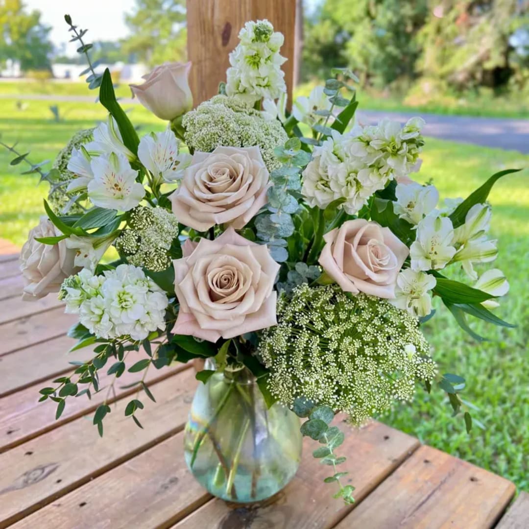 Blush roses and white flowers arranged in a glass vase