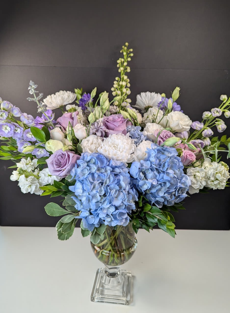 Lavender and blue floral arrangement in a clear glass vase