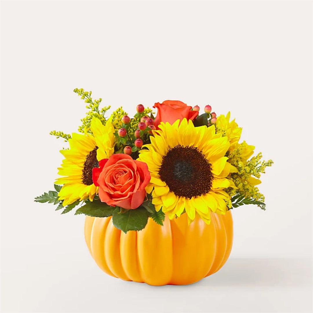 Sunflowers and orange roses arranged in a pumpkin-shaped container