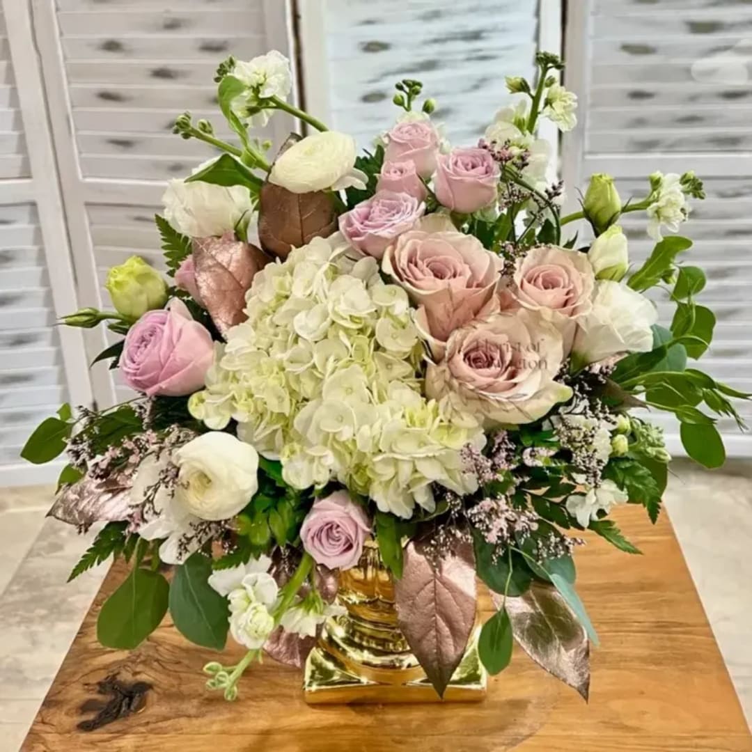 Pink roses and white hydrangeas arranged in a gold vase