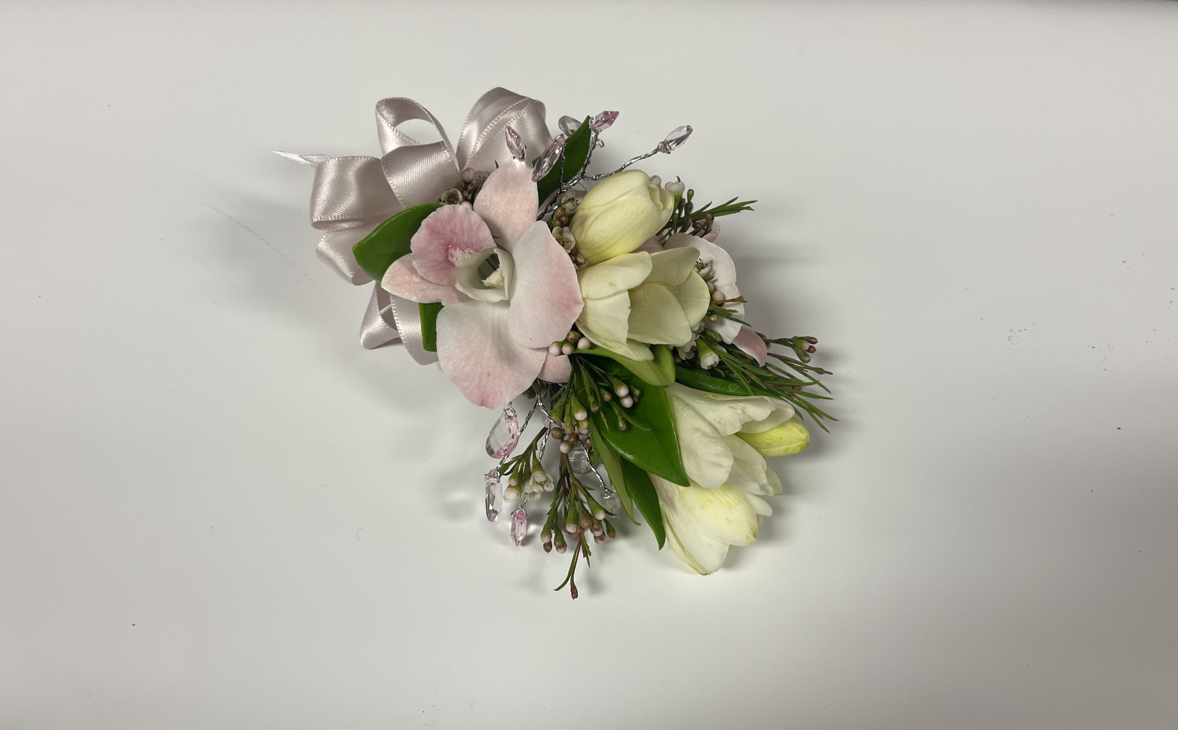 Small corsage of pale pink orchid and white blooms with ribbon and crystal accents