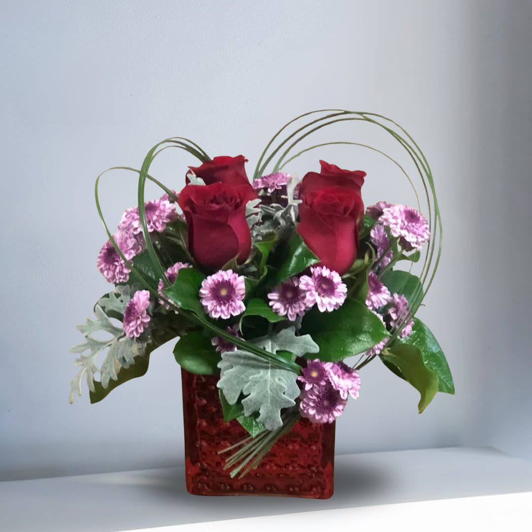 My Little Romance - Recipe: Red Roses, Purple Chrysanthemums, and greens in a short, red vase. Availability: All year round Design View: Front Facing View Photo shown: Regular 