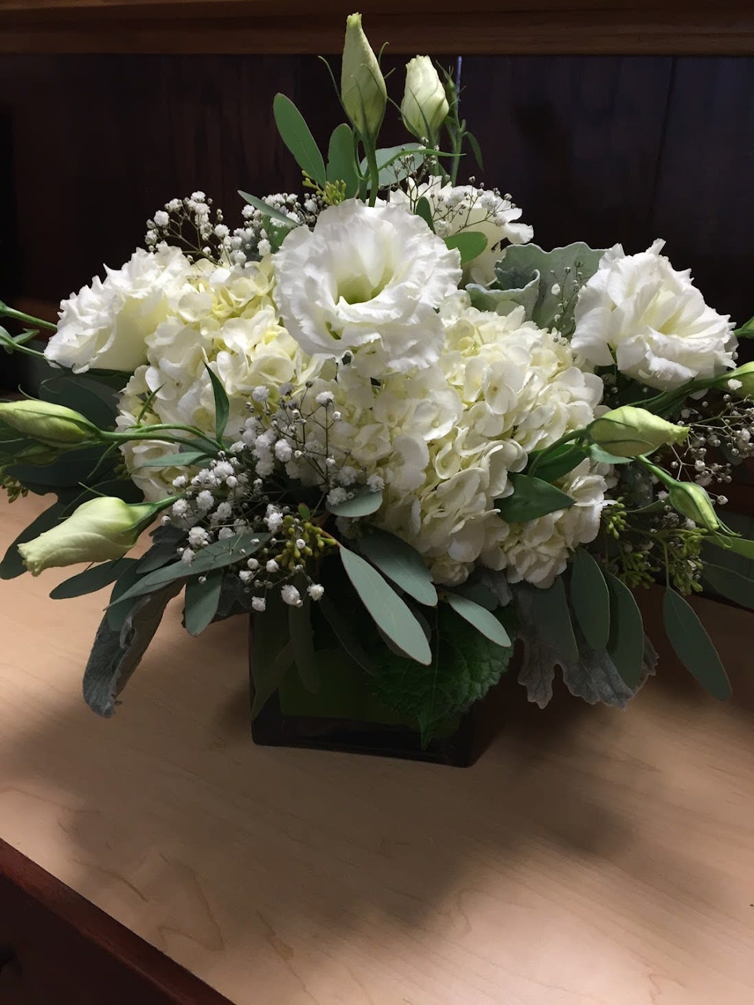 Timeless and Traditional Centerpiece - This classical traditional center piece is designed with white Hydrangaes, Lisianthus and Babies Breath with fresh Eucalyptus and Dusty Miller in a short vase. Availability: All year round Design View: All Facing View  Large quantites ust be order 5 days before event.