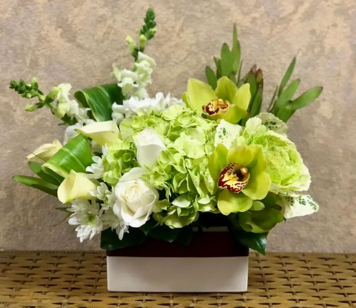Green and white floral arrangement in a rectangular box