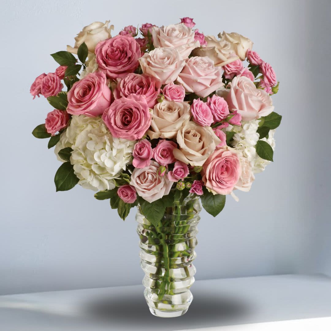 Pink and cream roses arranged in a clear glass vase