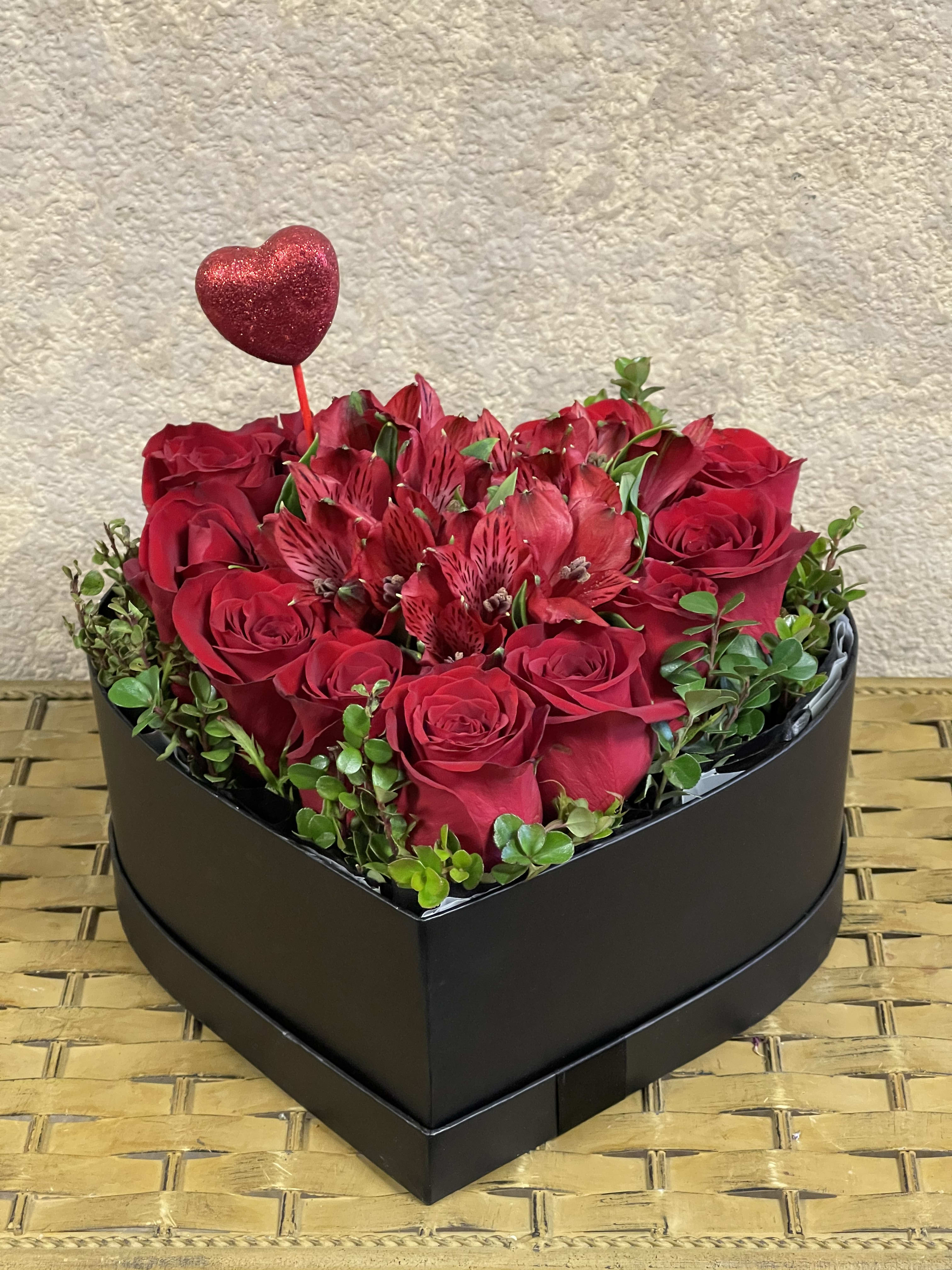 Heart-shaped box with Alstroemerias (available in all colors) - Type of Flowers: Red roses, red alstroemerias, and greens in a black heart-shaped box with a heart stick. Availability: All year round Substitute Available: Yes Design View: Symmetric Front Facing View Photo shown: Regular 