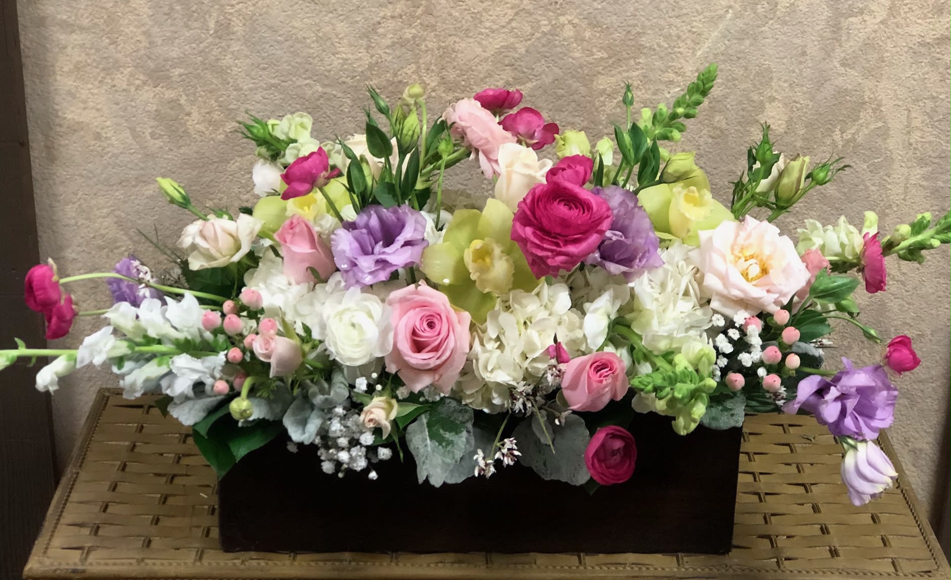 Mixed pink, white, and purple flowers in a black rectangular container