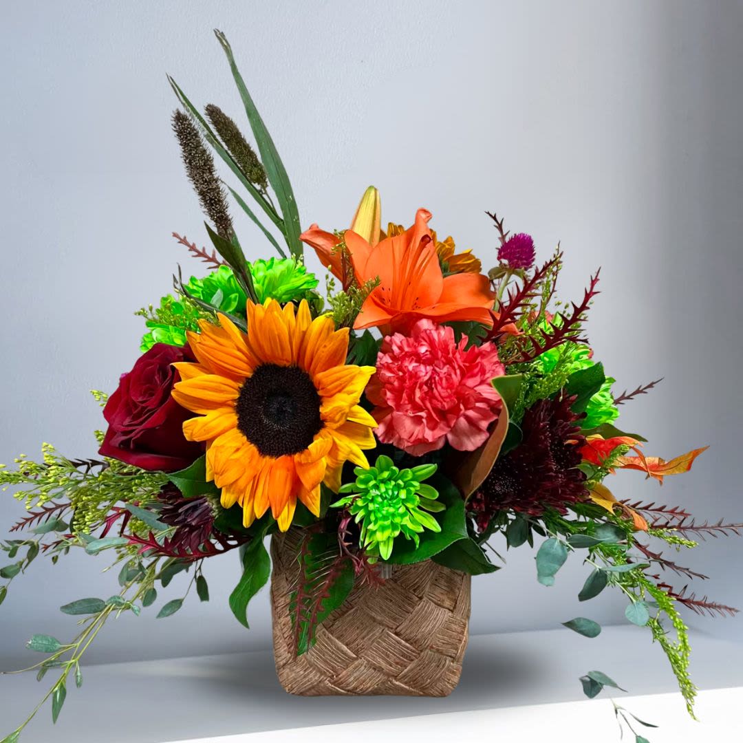 Thanksgiving Special - Recipe: Red Roses, Lilies, Green Chrsythemums, Sunflower, and green succulent in a brown "wicker style" pot you can use for plants later. Availability: Autumn Design View: Symmetric Front Facing View Photo shown: Standard 
