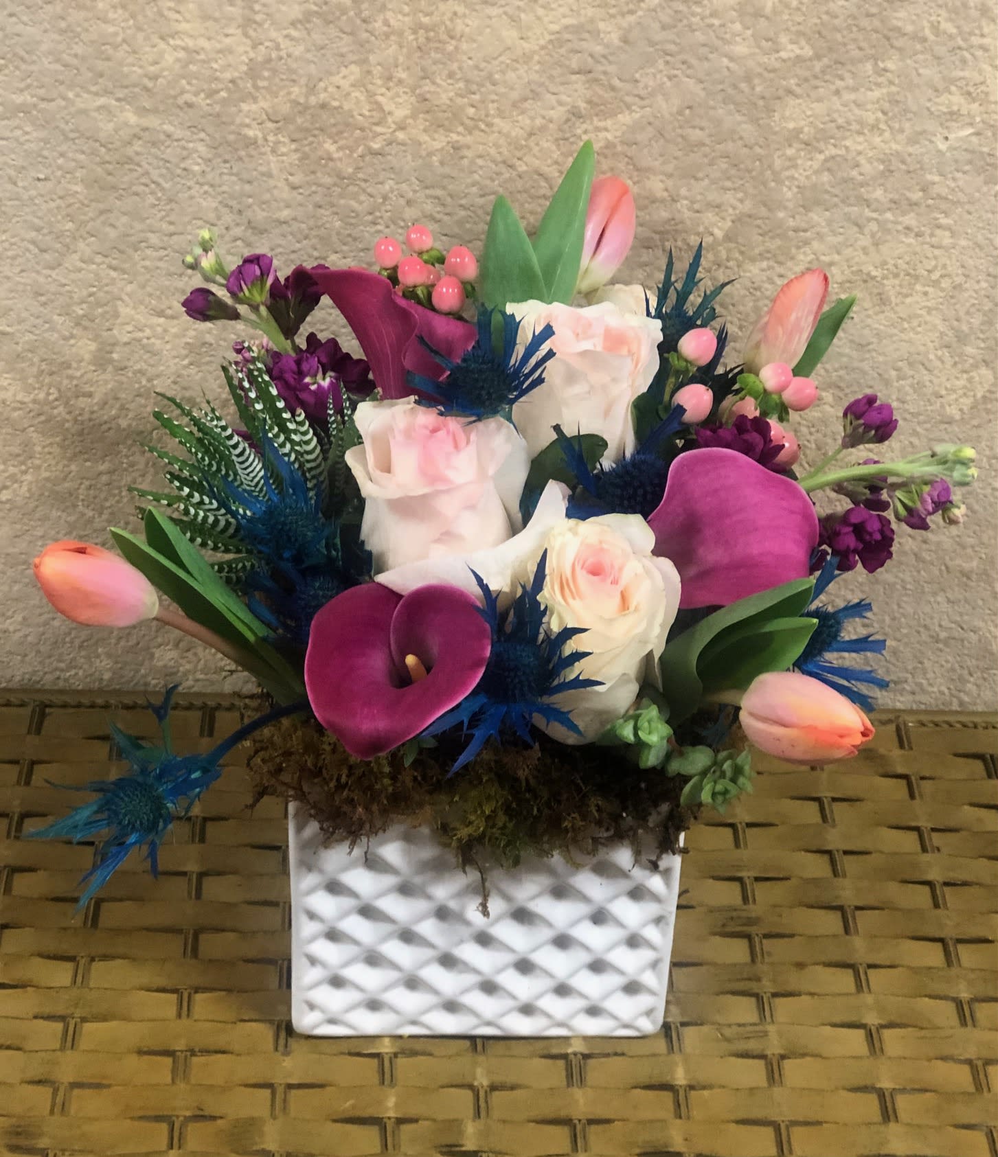 Winter Wonderland - Wonderland-inspired arrangement! Recipe: Includes Blush roses, tulips, mini calla lilies, berries, stock, and succulents in a white square vase with moss. Seasonal: Limited Availability Design View: All Facing View Photo shown: Standard 
