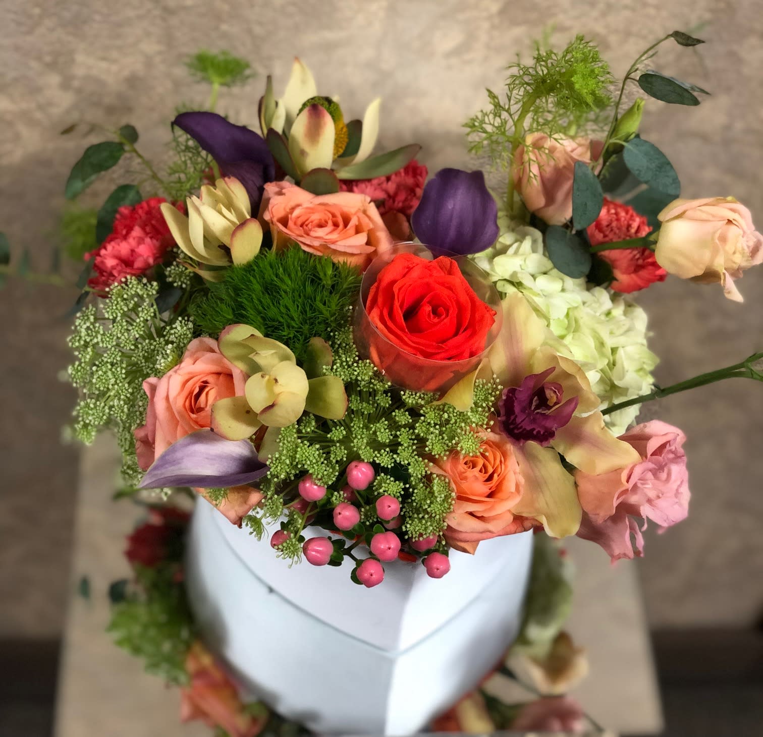 Eternity - Spring color florals in a heart-shaped box. Perfect for Moms. Type of flowers: Tulips, orange roses, orchids, lisianthus, and carnations with an eternal heart in the center in a heart-shaped box. Availability: All year round Substitute Available: Yes Design View: All Facing View Photo shown: Regular