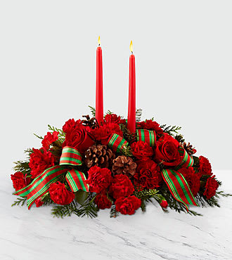 The FTD® Holiday Classics™ Centerpiece - Share the joy of the season with a centerpiece full of festive blooms and gorgeous season's greetings. A collection of bright red roses, carnations and mini carnations are elegantly put together among assorted holiday greens and fresh, natural pinecones. Our Holiday Classics Centerpiece is completed with two tall, red taper candles and a red and green striped ribbon that truly capture the magic of the holiday's. This arrangement is perfect for decorating any table for your holiday gatherings. This centerpiece is approximately 6"H x 17"W.