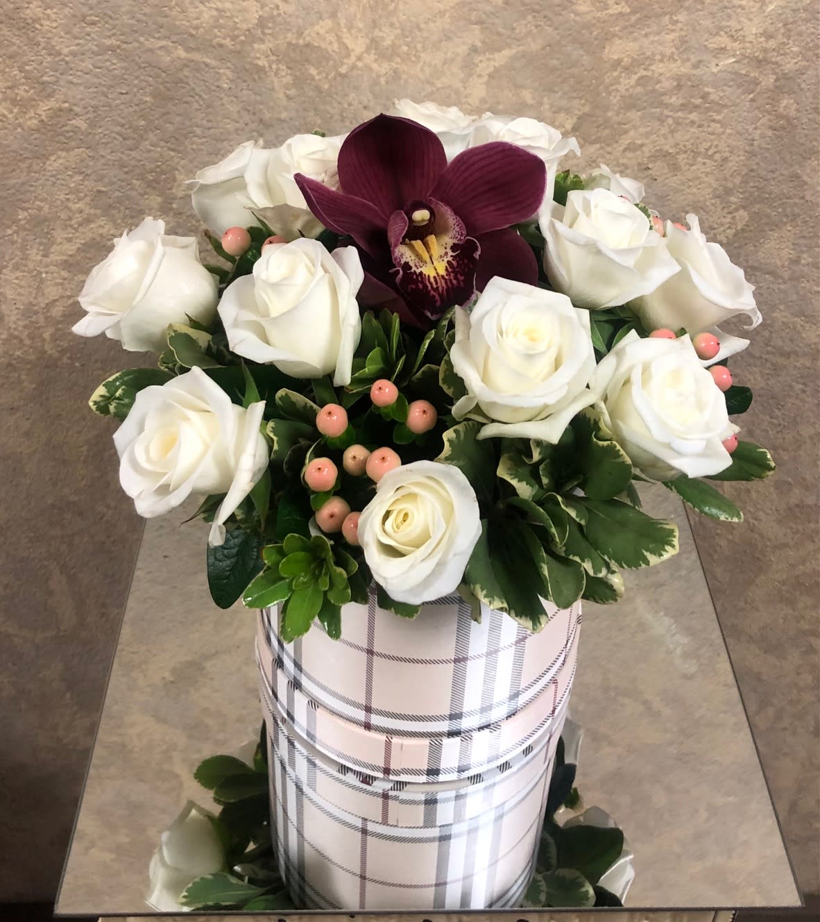 Burberry Beauty (Black Plaid Only Available) - Recipe: White roses, burgundy orchid, and berries in a beautiful black plaid cylinder box only available. Availability: All year round Substitute: Black plaid box Seasonal: All year round Design View: All Facing View Photo shown: Standard 