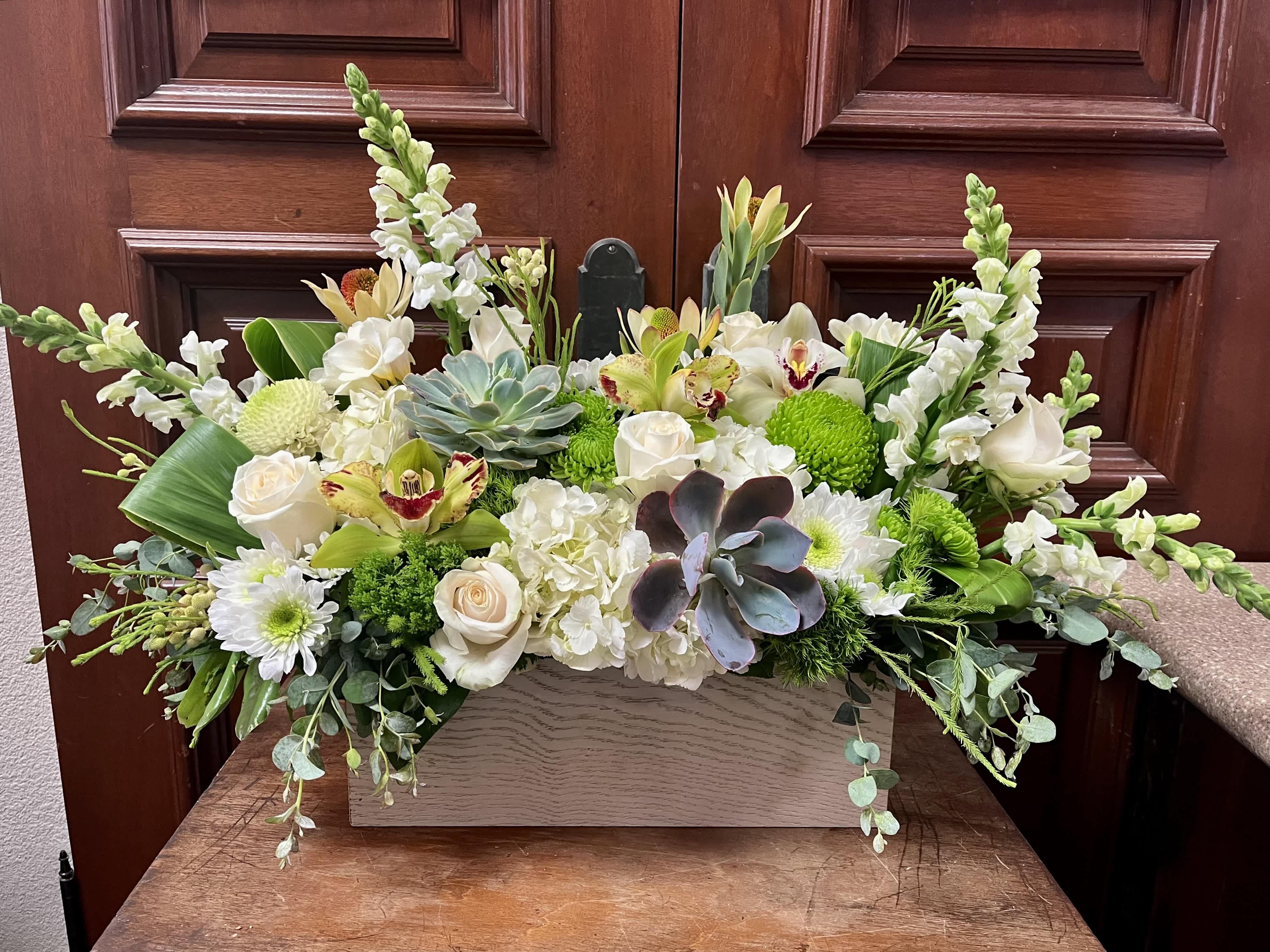 Peace on Earth - Recipe: White Hydranages, White Snapdragons, White Chrysanthemums, White Roses, Green and White Orchids, Freesia, Green Buttons, Dianthus Barbatus, Safari and succulents in a long, white vase. Availability: All year round Design View: Symmetric Front Facing View Photo shown: Standard 