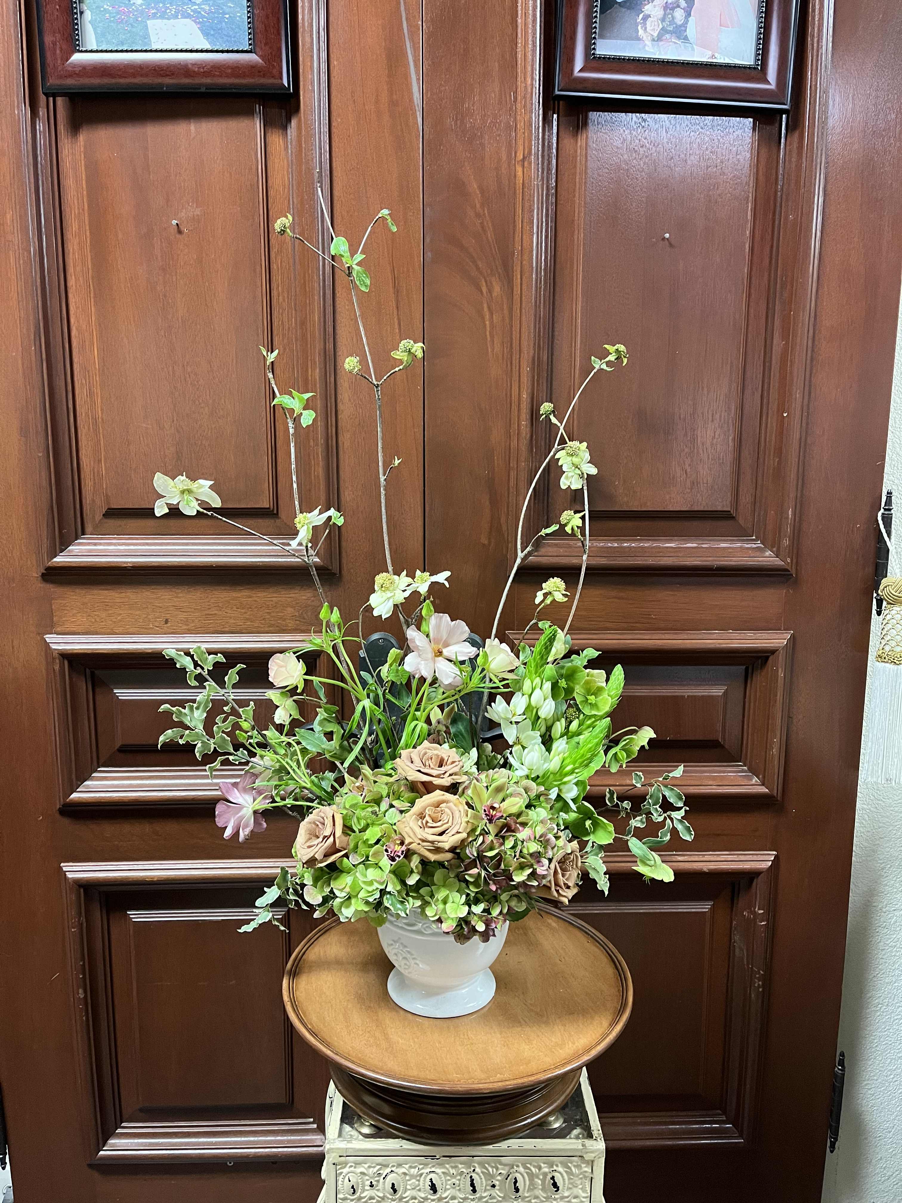 Spring's Seasonal Blooms - Recipe: Seasonal Dogswood, Seasonal hellesbore, Seasonal butterfly ranuculus, seasonal hyancith, antique green hydrangaes, mini green cymbidium orchids, antique brown roses and more in a white vase. Availability: Spring Design View: Front Facing View Photo shown: Standard 