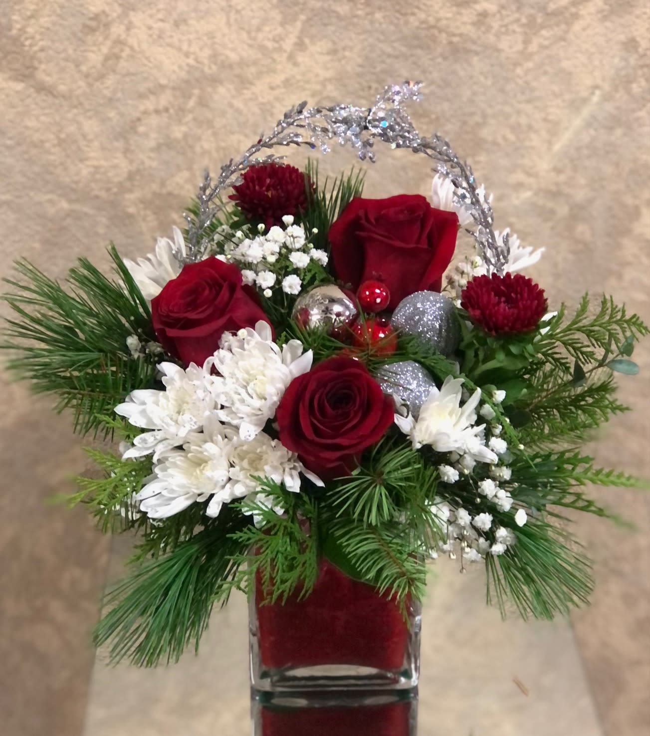 From: Me To: You - Send holiday tidings with this festive arrangement.  Arrangement includes red roses, white aster, red matsumoto, ornaments, and Christmas greens in a short red wrapped square vase.