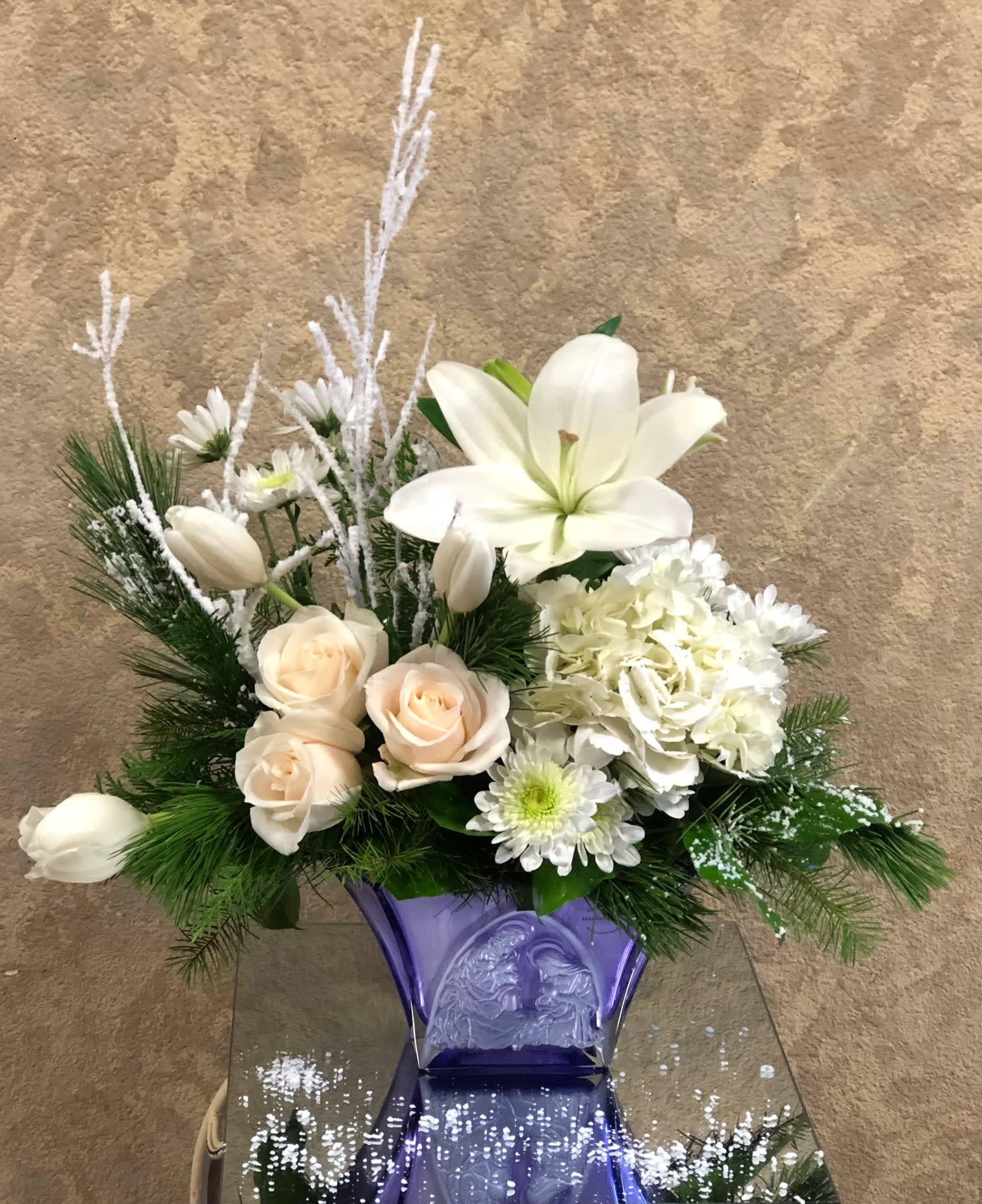 Crystal Nativity - Tiger lily, light pink roses, hydrangea, tulips, mums, and pine greens in a crystal nativity vase.