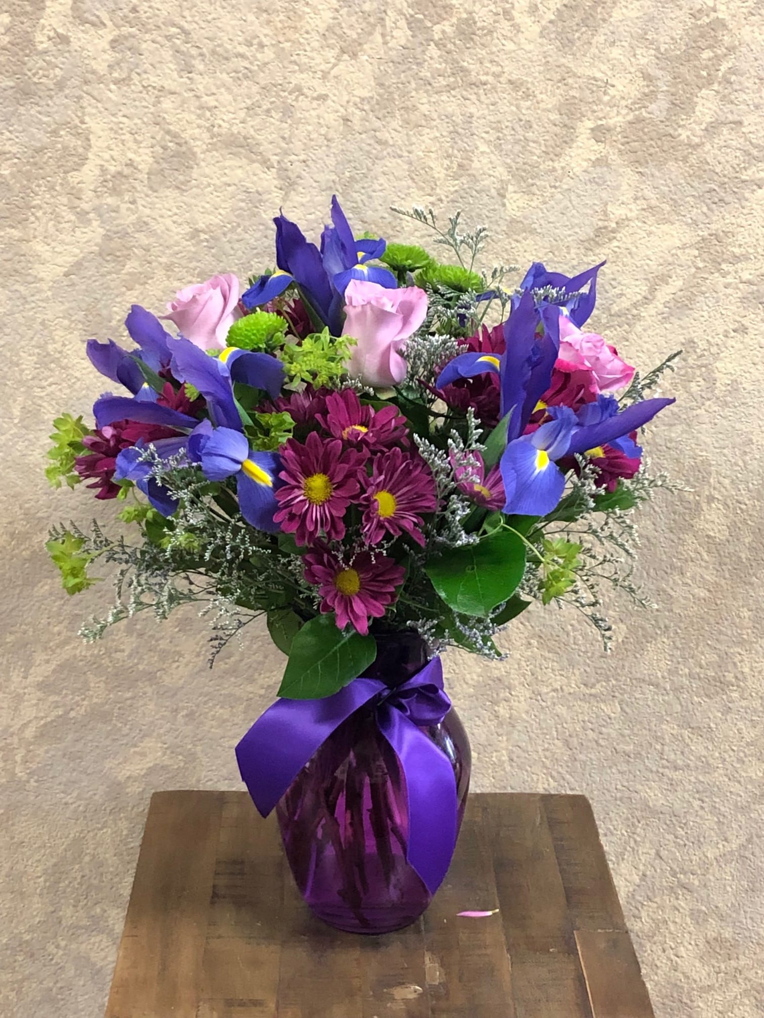 Bouquet of purple irises and pink daisies in a purple vase