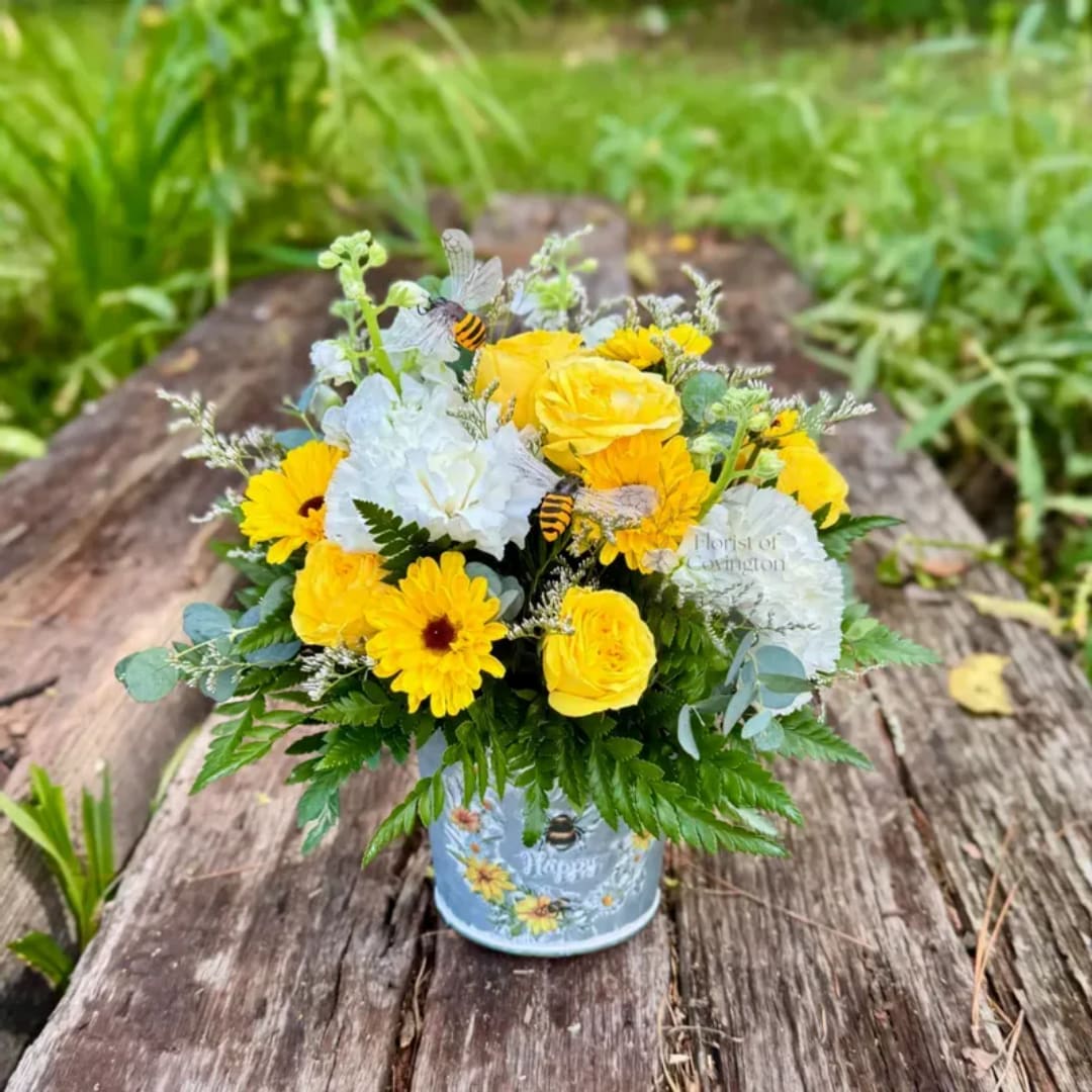 Yellow and white mixed flower arrangement in a blue tin container