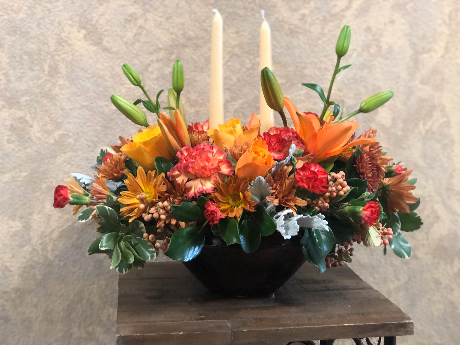 Happy Thanksgiving Centerpiece - Type of Flowers: Orange Roses, Orange Asiatic Lilies, Fall-colored Daisies, Red Carnations, Hypericum, and green succulent in a vase with candlesticks. Availability: All year round Substitute Available: Yes Design View: All-sided Facing View Photo shown: Regular