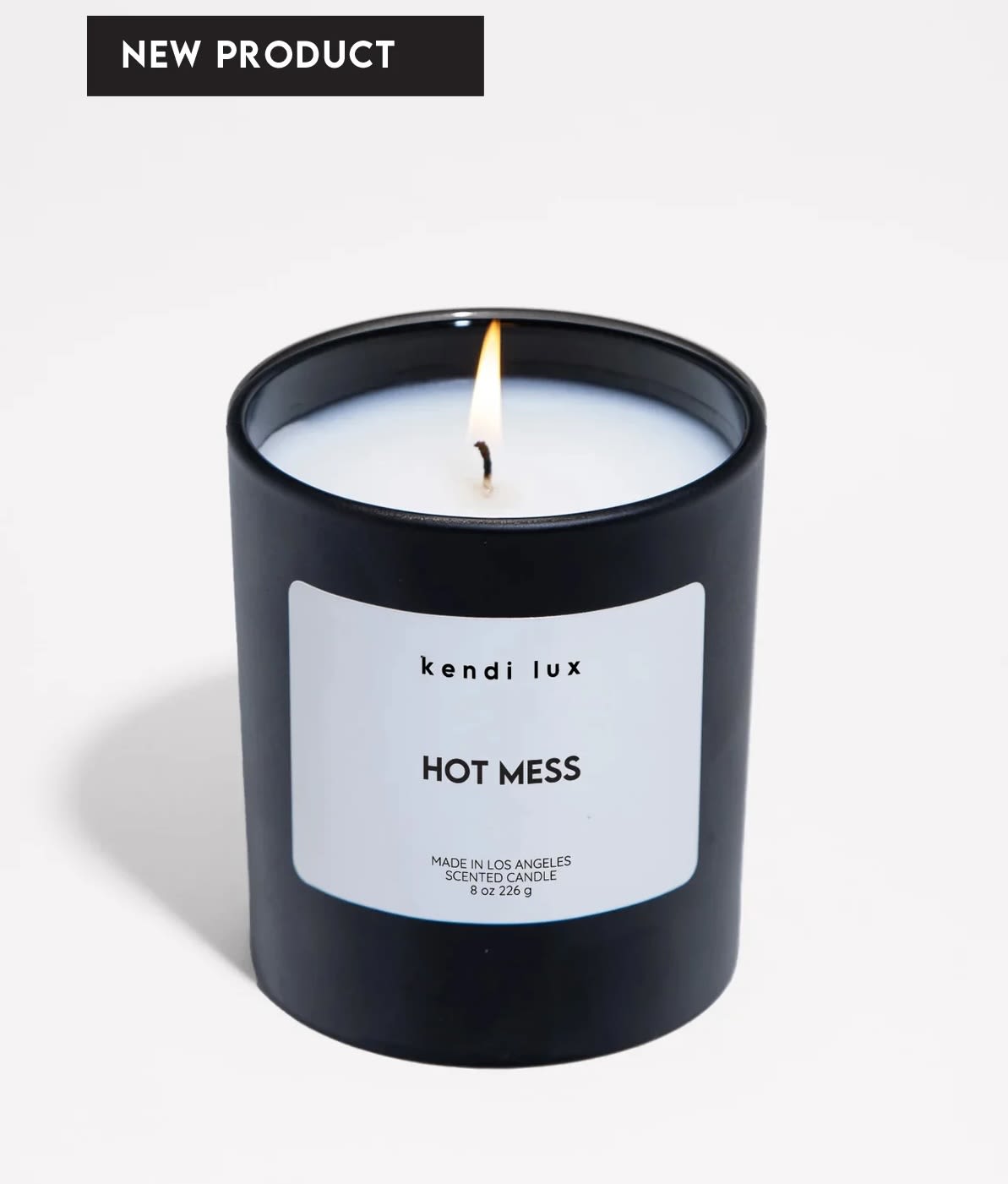 Lit black scented candle in a glass jar with a white label