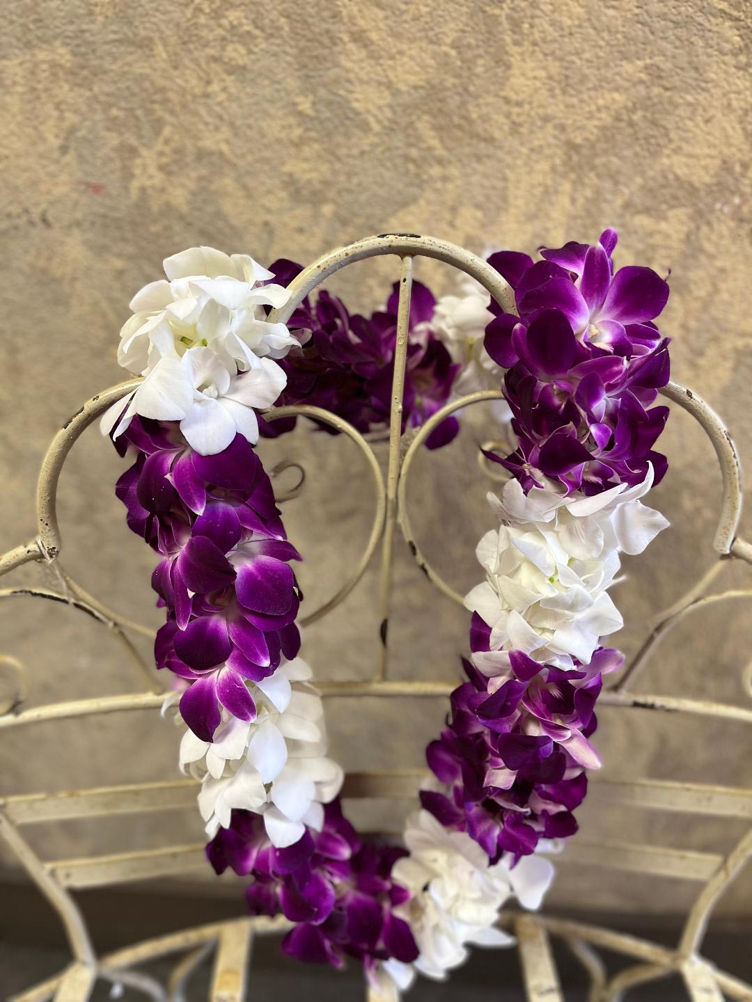 Purple and white orchid leis draped over a metal chair