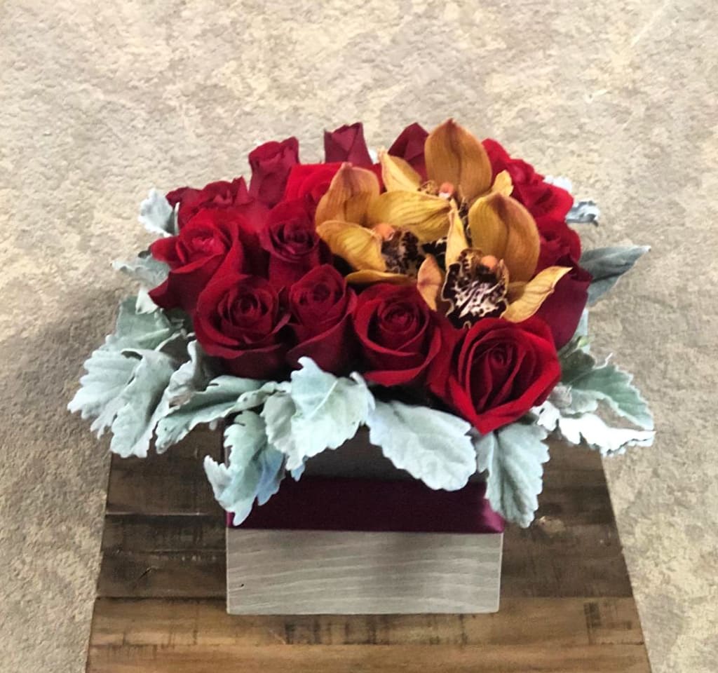 You are a Gift - Type of Flowers: Cymbidium Orchid, Red Roses, and Dusty Miller in a square wooden box wrapped in red ribbon. Availability: All year round Substitute Available: Yes Design View: Front Facing View Photo shown: Regular 