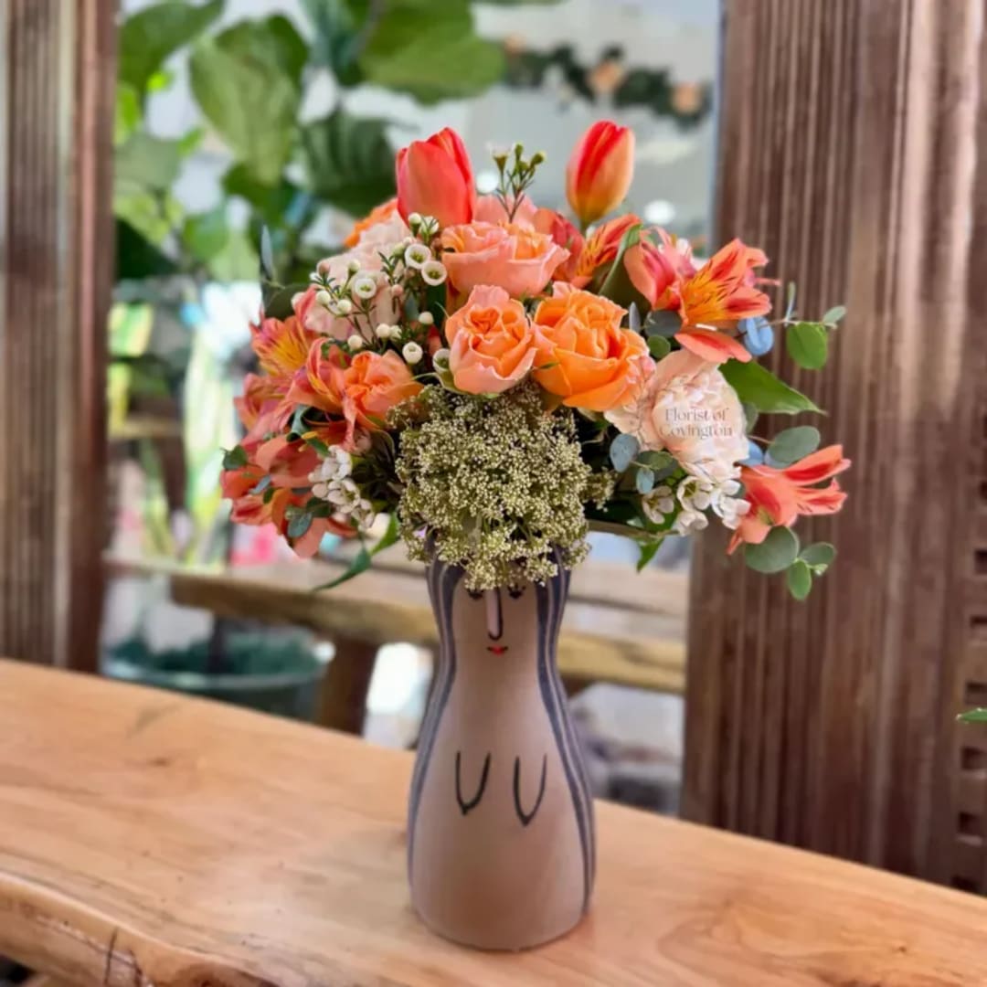 Orange and peach bouquet in a painted ceramic vase