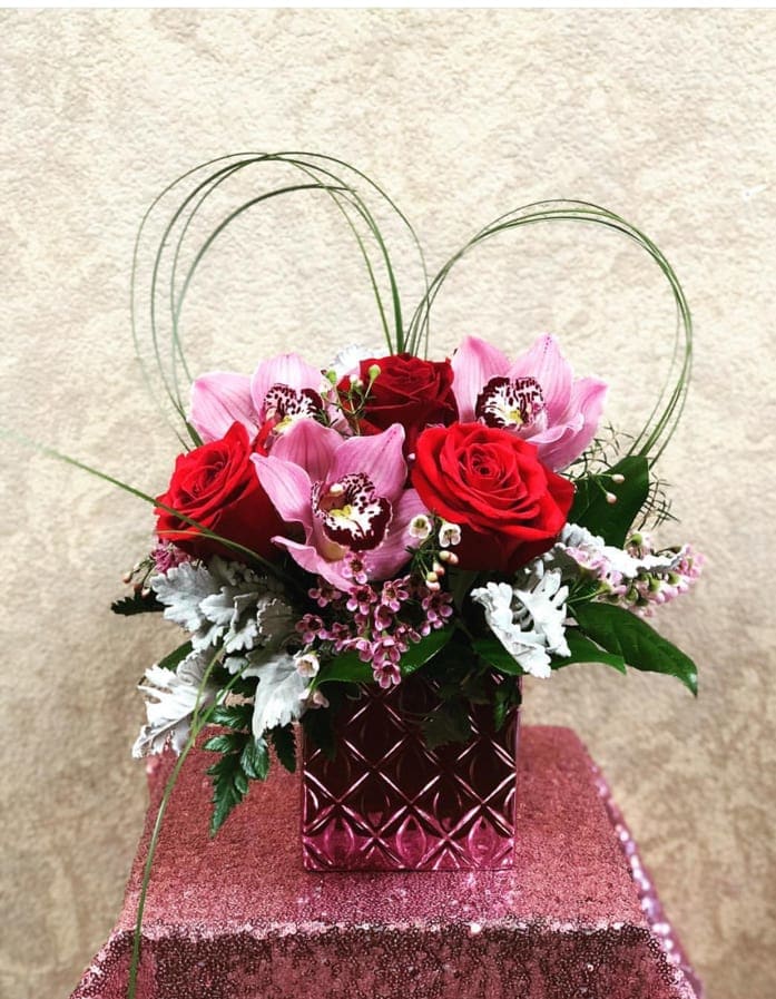 You Are Loved - Type of Flowers: Cymbidium Orchids and Red Roses with bear grass in a short pink vase. Availability: All year round Substitute Available: Yes Design View: All Facing View Photo shown: Regular  Only deluxe and premium are available for delivery. please call 