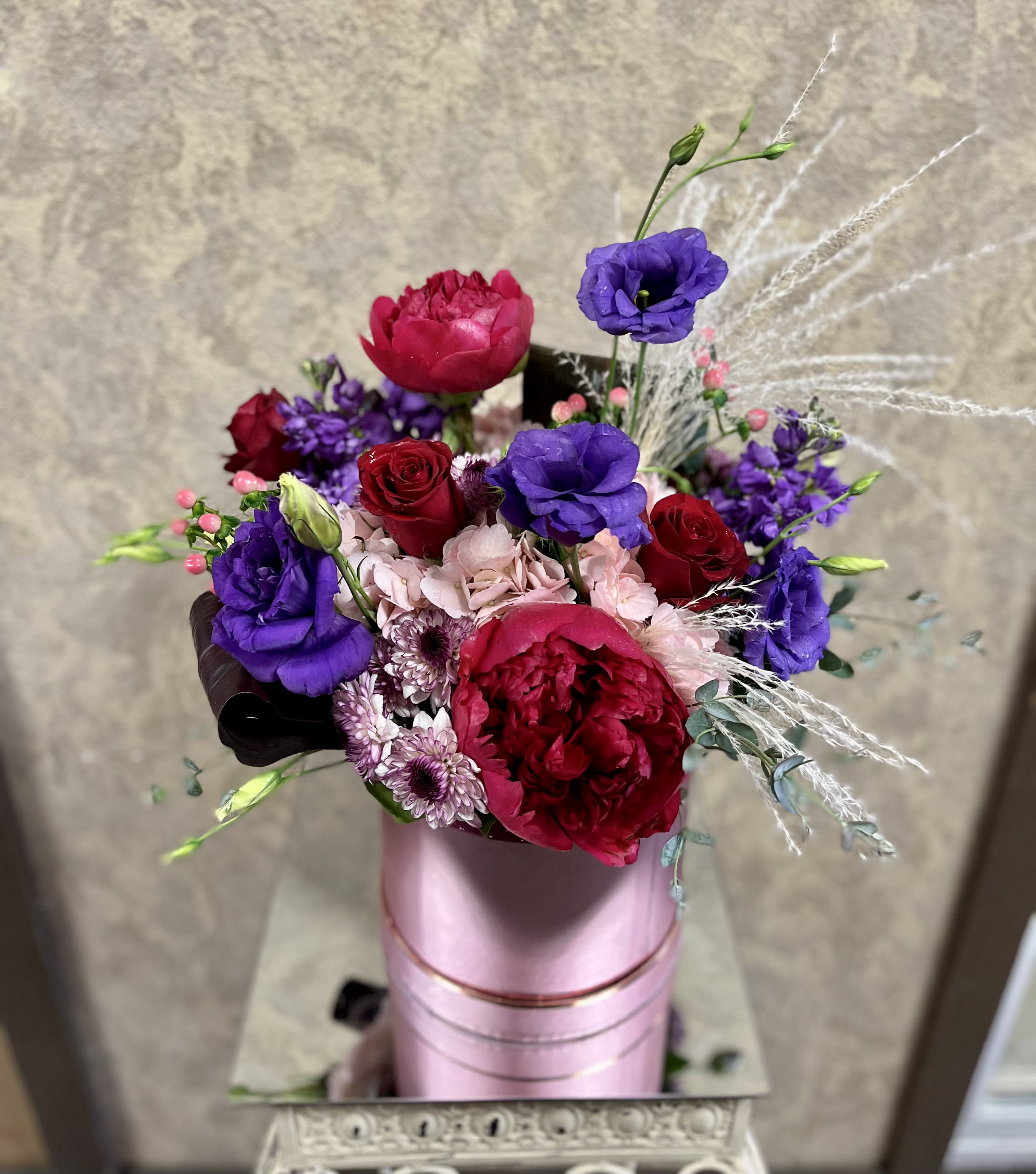 XO - Send hugs and kisses with this exquisitely, romantic design. Type of Flowers: Red peonies, Purple Lisianthus, Purple Stock, Red Roses, Pink Hydrangeas, Pink Hypericum Berries, and purple leaves in a pink box with lid. Availability: All year round Substitute Available: Yes Design View: Symmetric Front Facing View Photo shown: Regular 