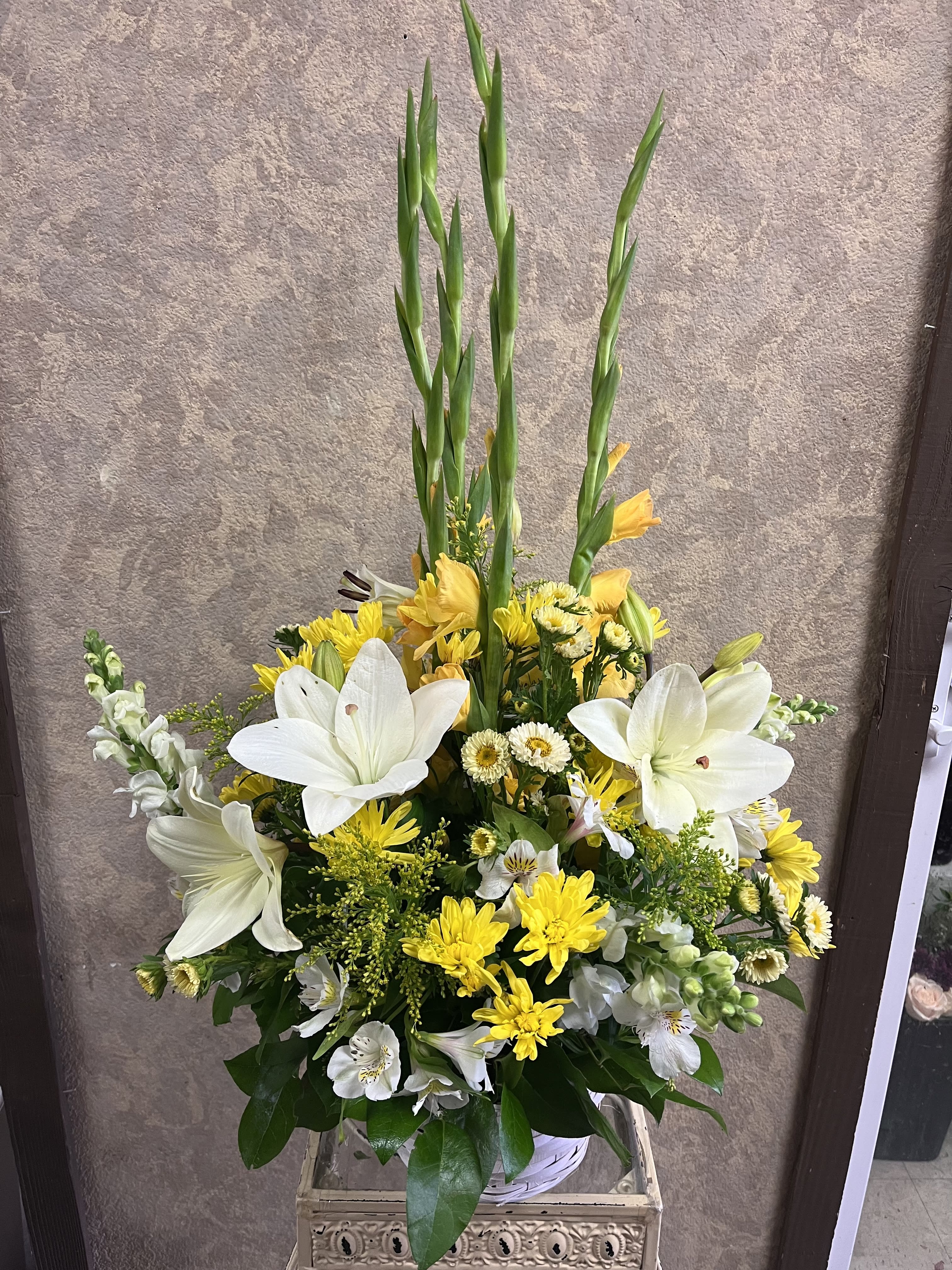 Tall white and yellow floral arrangement with lilies and gladiolus in a basket