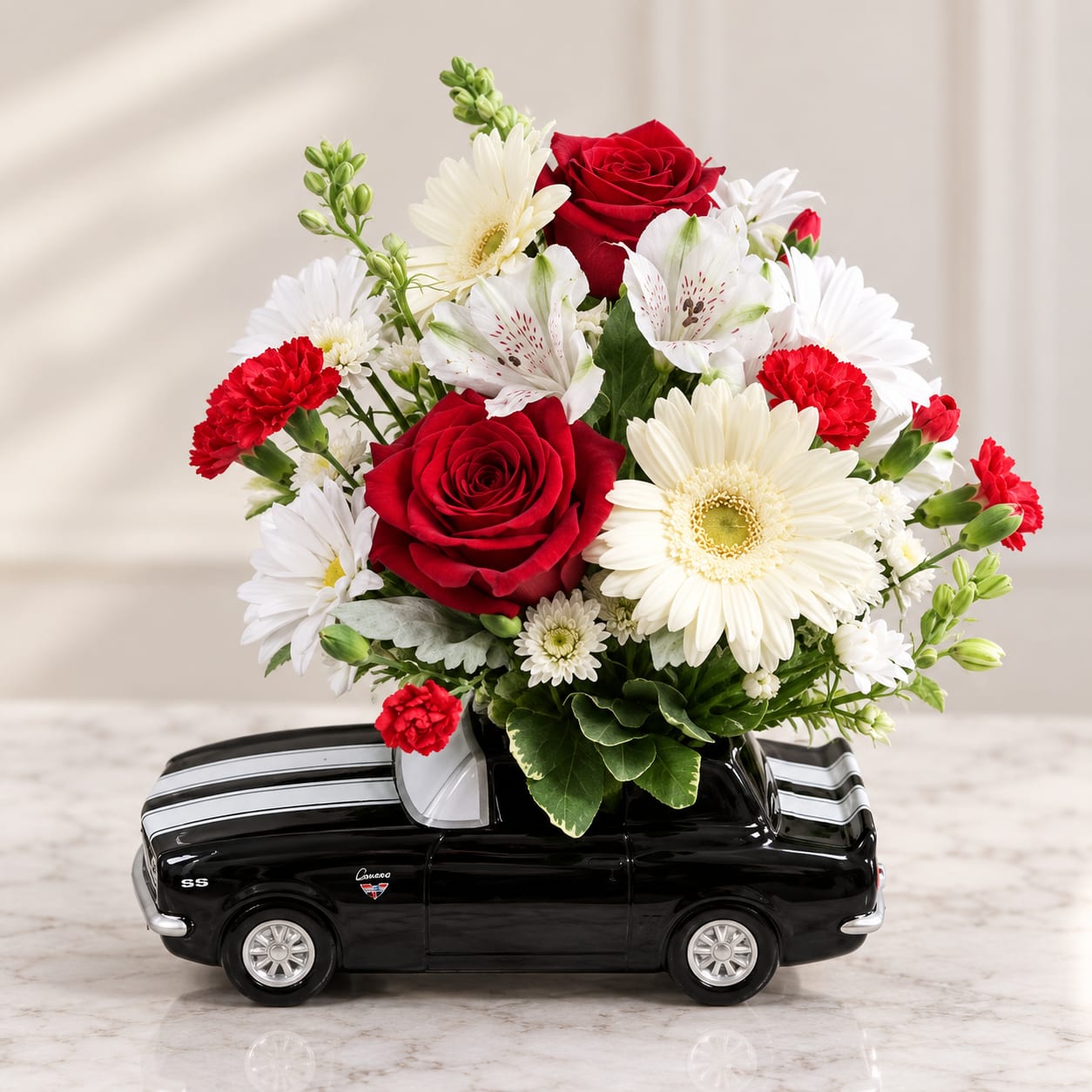 Red roses and white daisies arranged in a black car-shaped container