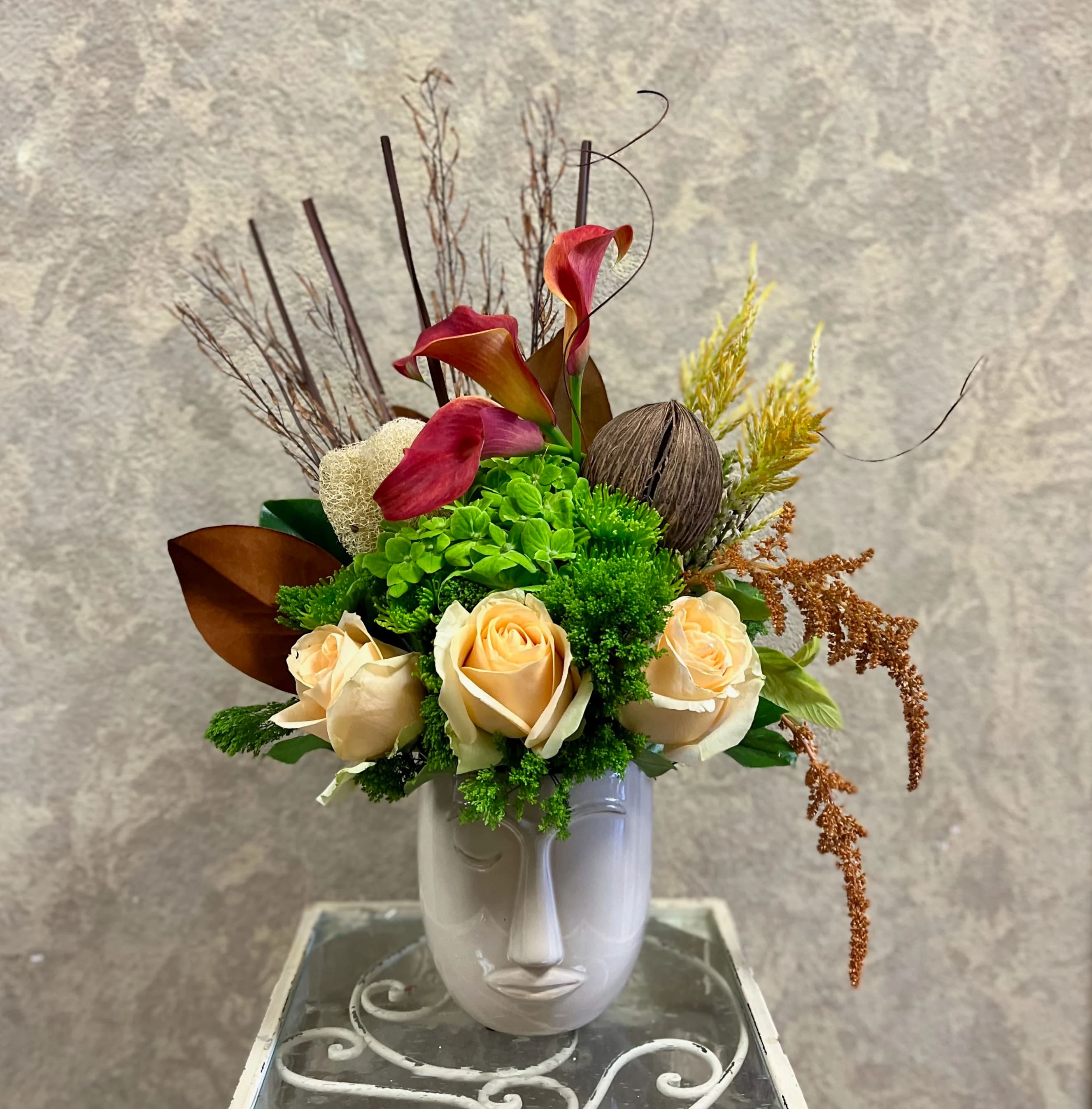 Sedona, Arizona - Type of Flowers: Calla Lilies, Hydrangeas, Roses, Branches, Sorghum, and more in one eye closed, abstract face ceramic pot. Availability: All year round Design View: Symmetric Front Facing View Photo shown: Standard  Choose white, beige or pink face pot.