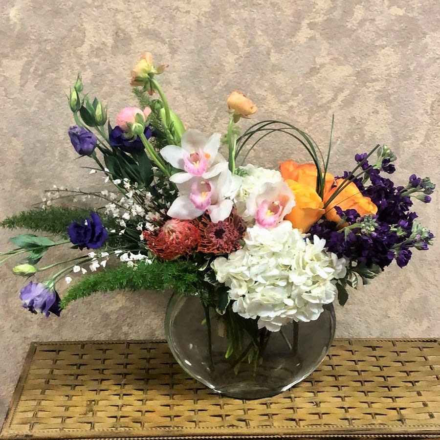 Mixed bouquet in a clear glass vase with white, purple, orange, and pink blooms